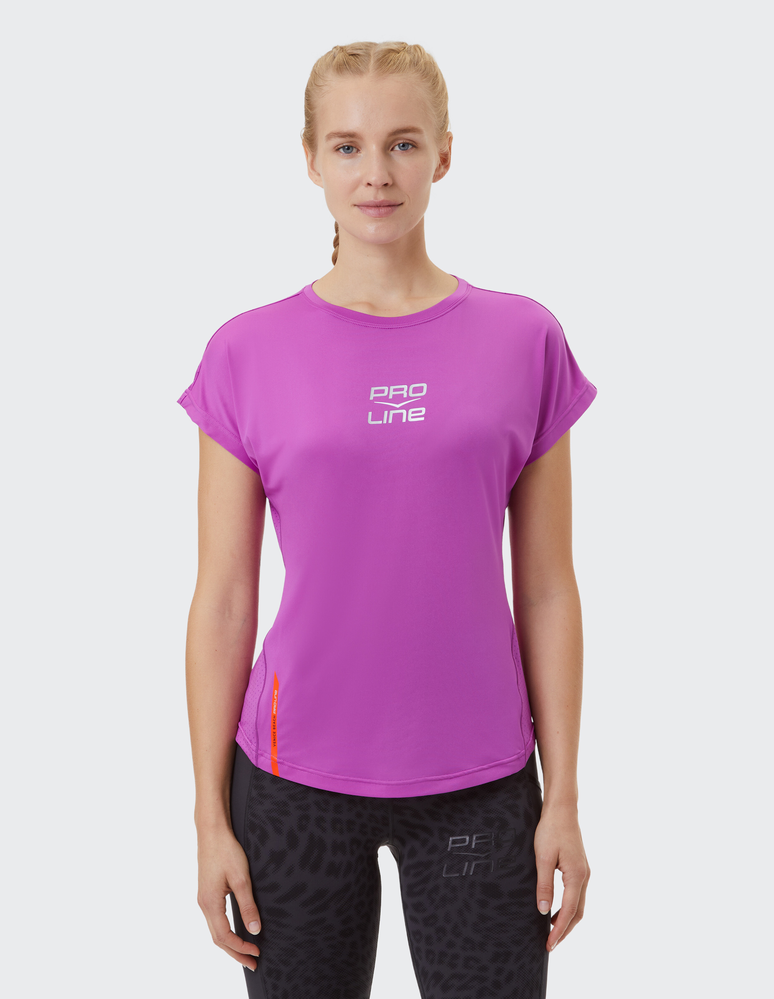 Frau trägt ein rosa PRO LINE-T-Shirt, gepaart mit schwarz gemusterten Leggings.