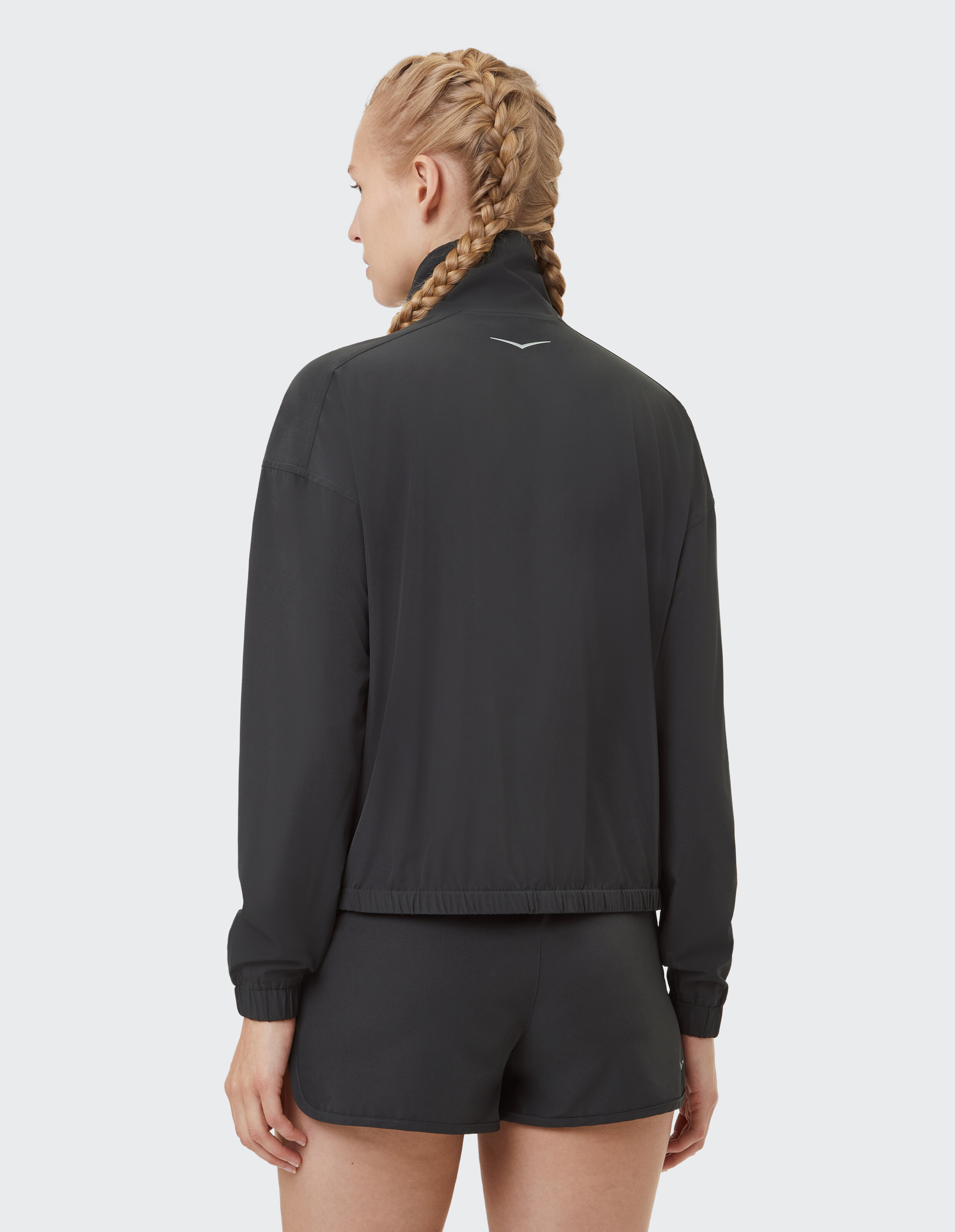 Frau trägt eine schwarze, lässige Jacke mit Reißverschluss, hohem Kragen und passenden Shorts.