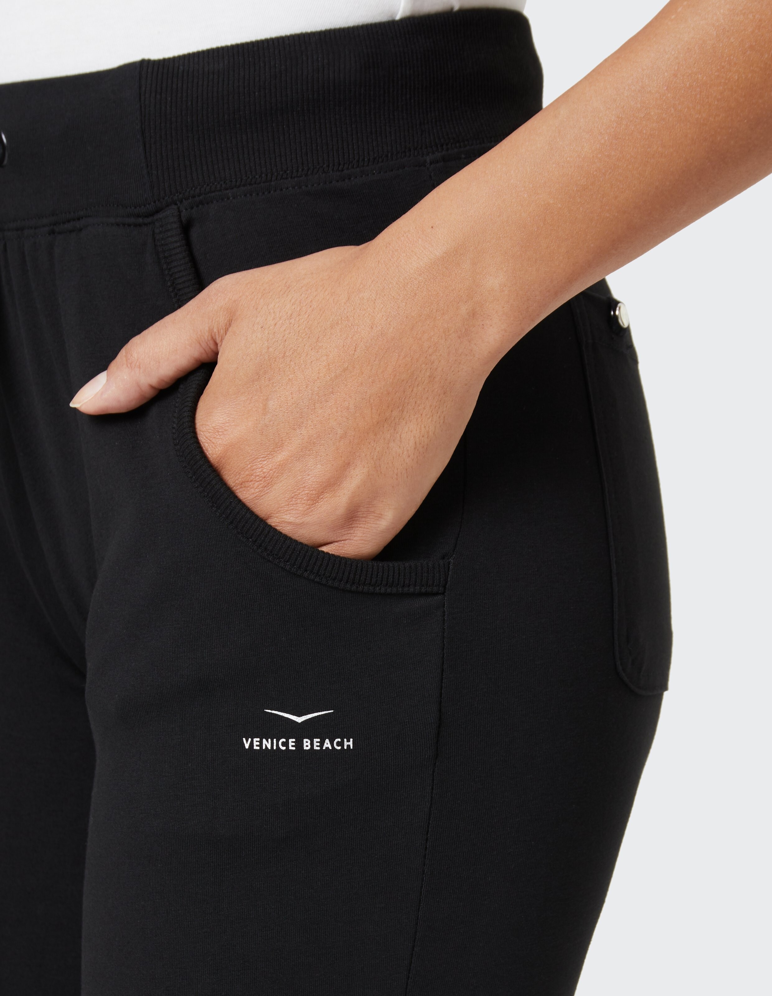 Nahaufnahme einer schwarzen Freizeithose mit Taschen und Venice Beach-Logo.