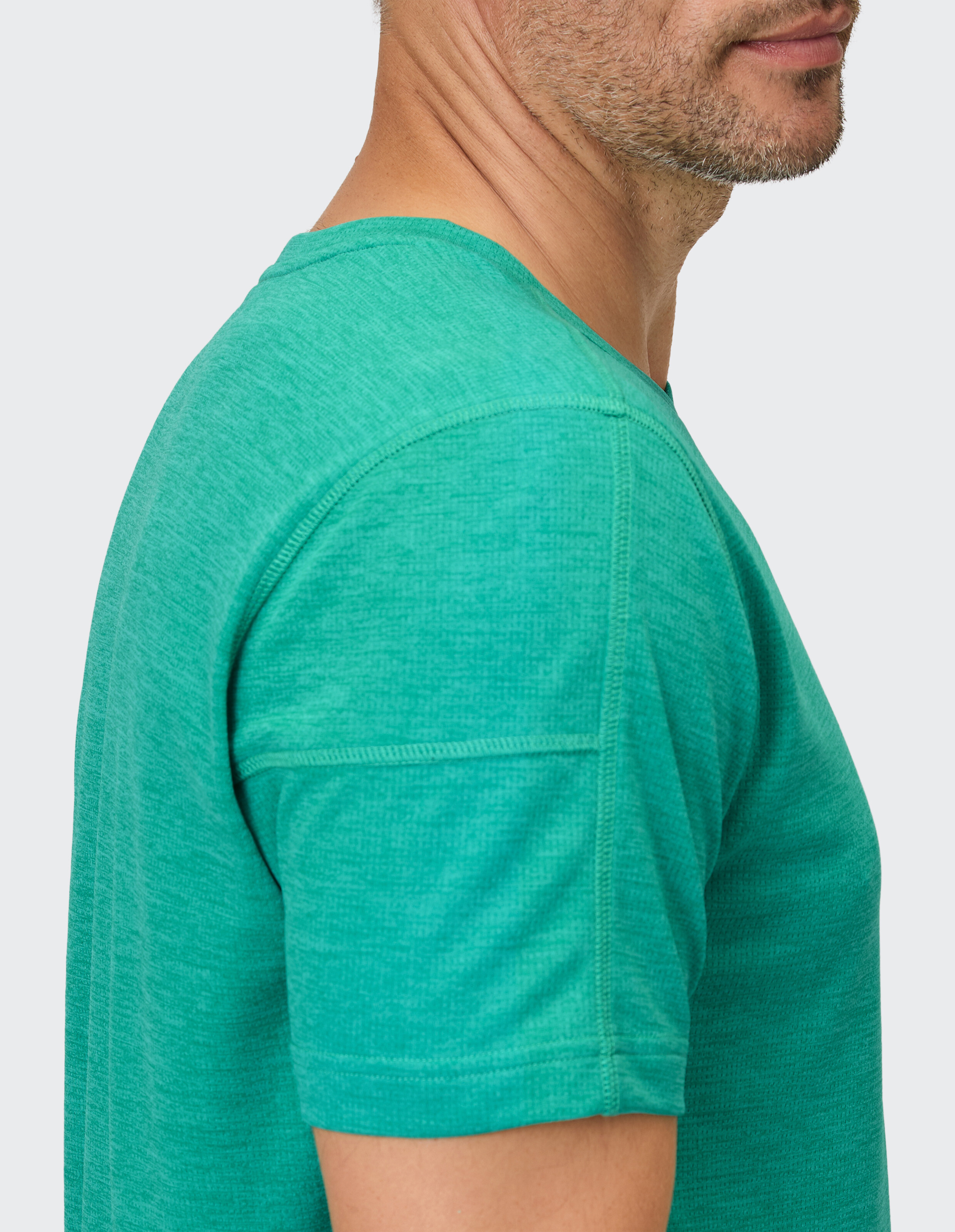 Nahaufnahme eines Mannes, der ein grünes, kurzärmliges Freizeit-T-Shirt trägt und eine weiche Textur zeigt.