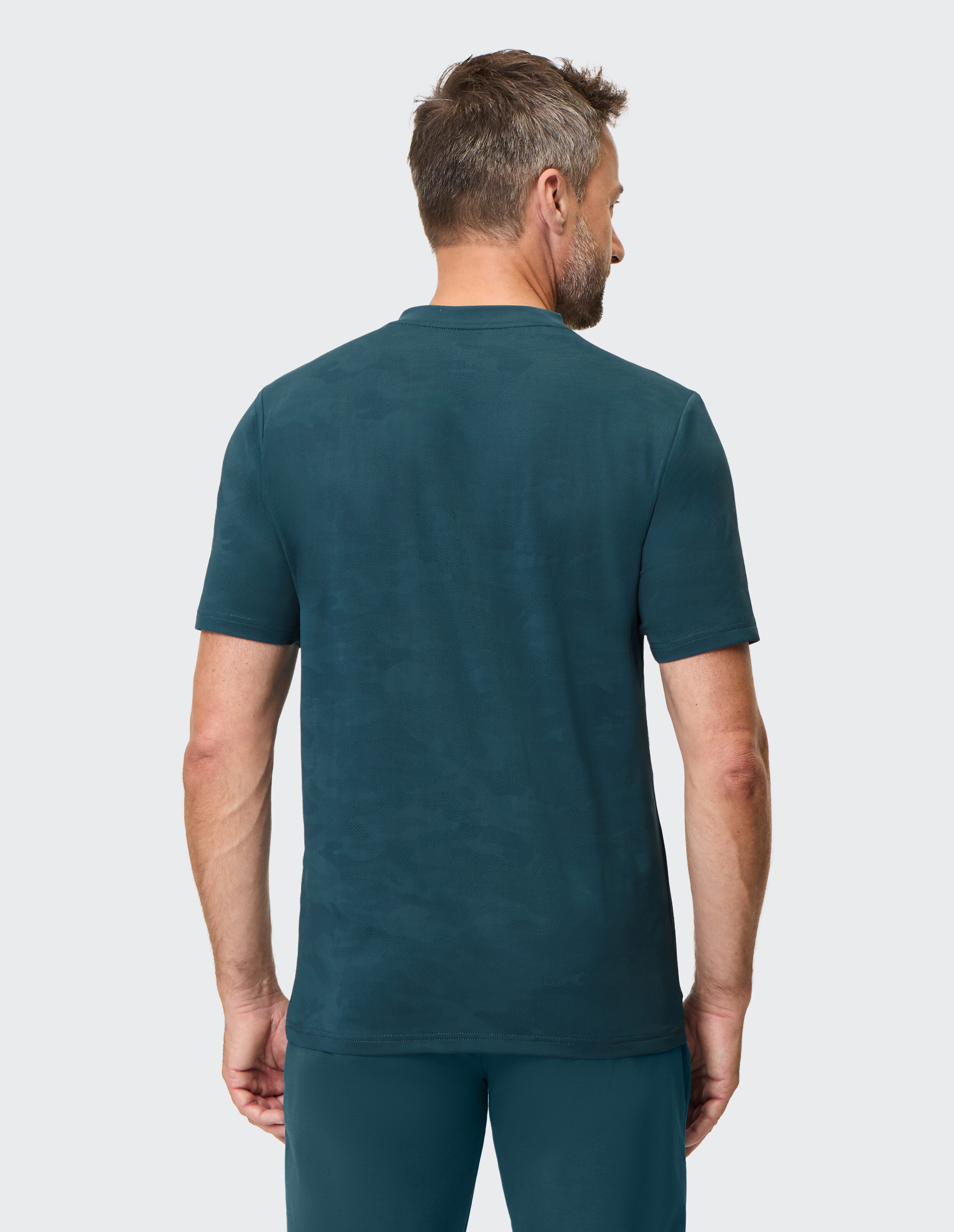 Dunkelgrünes T-Shirt mit V-Ausschnitt und kurzem Ärmel, dezentes Logo auf der Brust, ideal für sportliche Aktivitäten.
