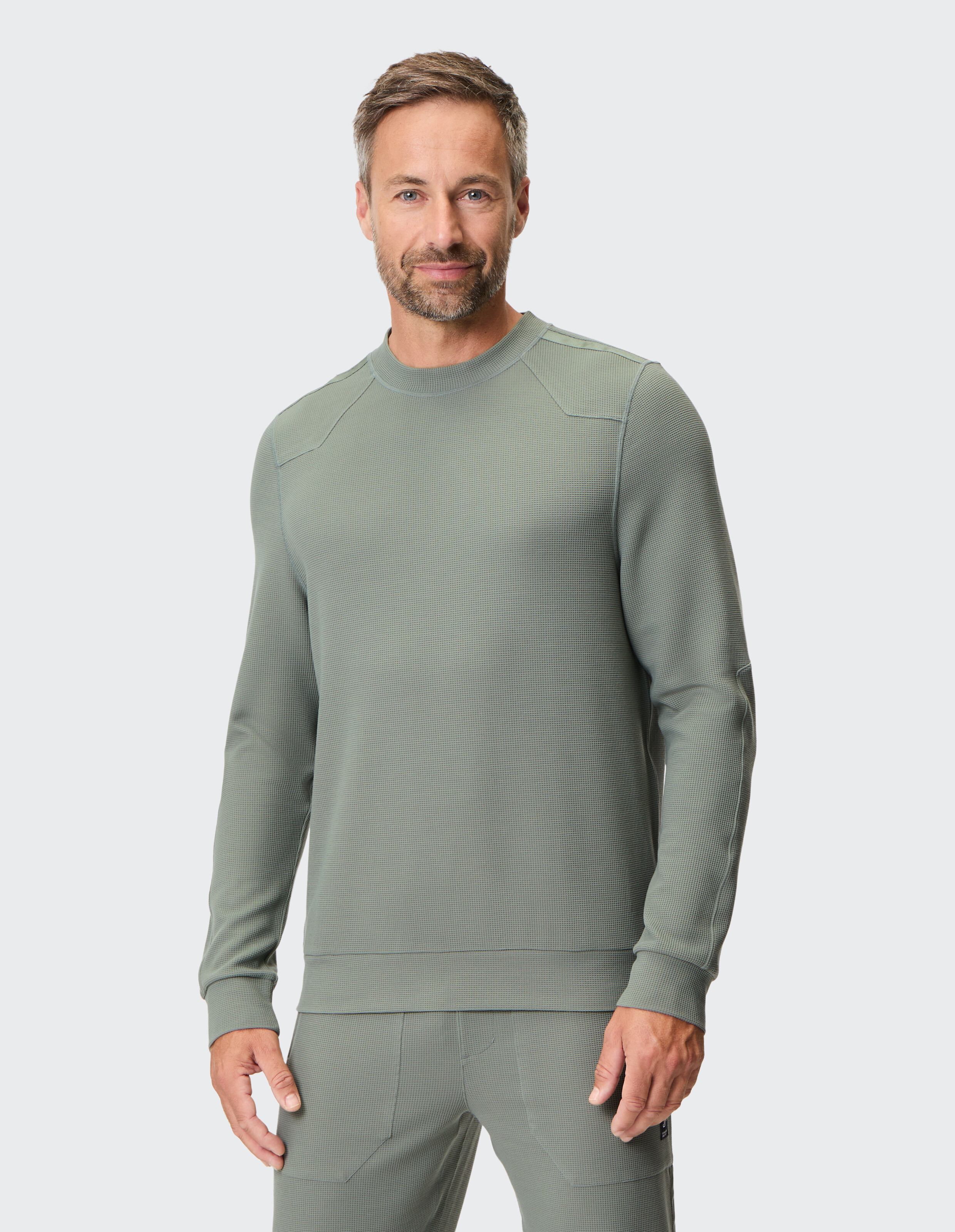 Grauer Pullover mit Rundhalsausschnitt und langen Ärmeln, gefertigt aus strukturiertem Stoff mit dezentem, geometrischem Muster.