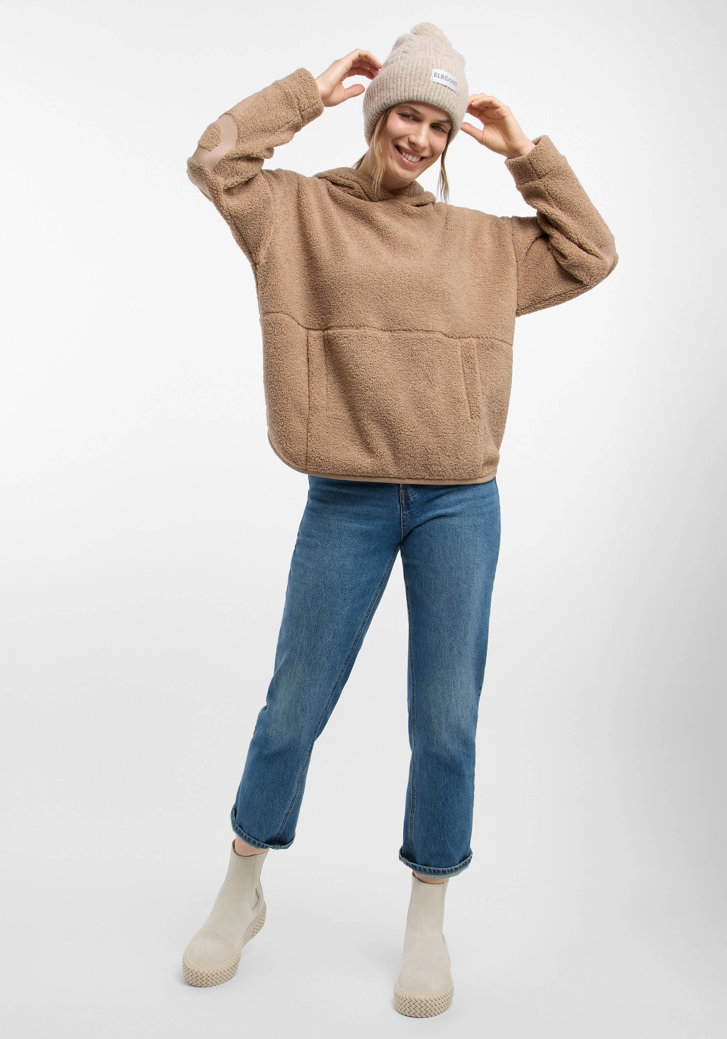 Kuscheliger beiger Fleecepullover mit Vordertasche, gepaart mit Blue Jeans und beigen Stiefeln.