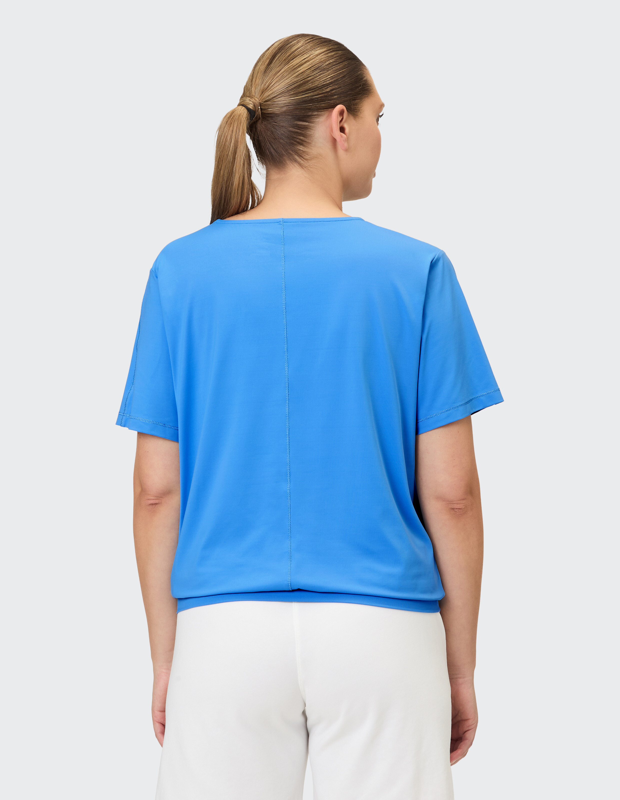 Rückansicht einer Frau, die ein blaues Freizeitoberteil trägt, perfekt für entspannte Ausflüge.