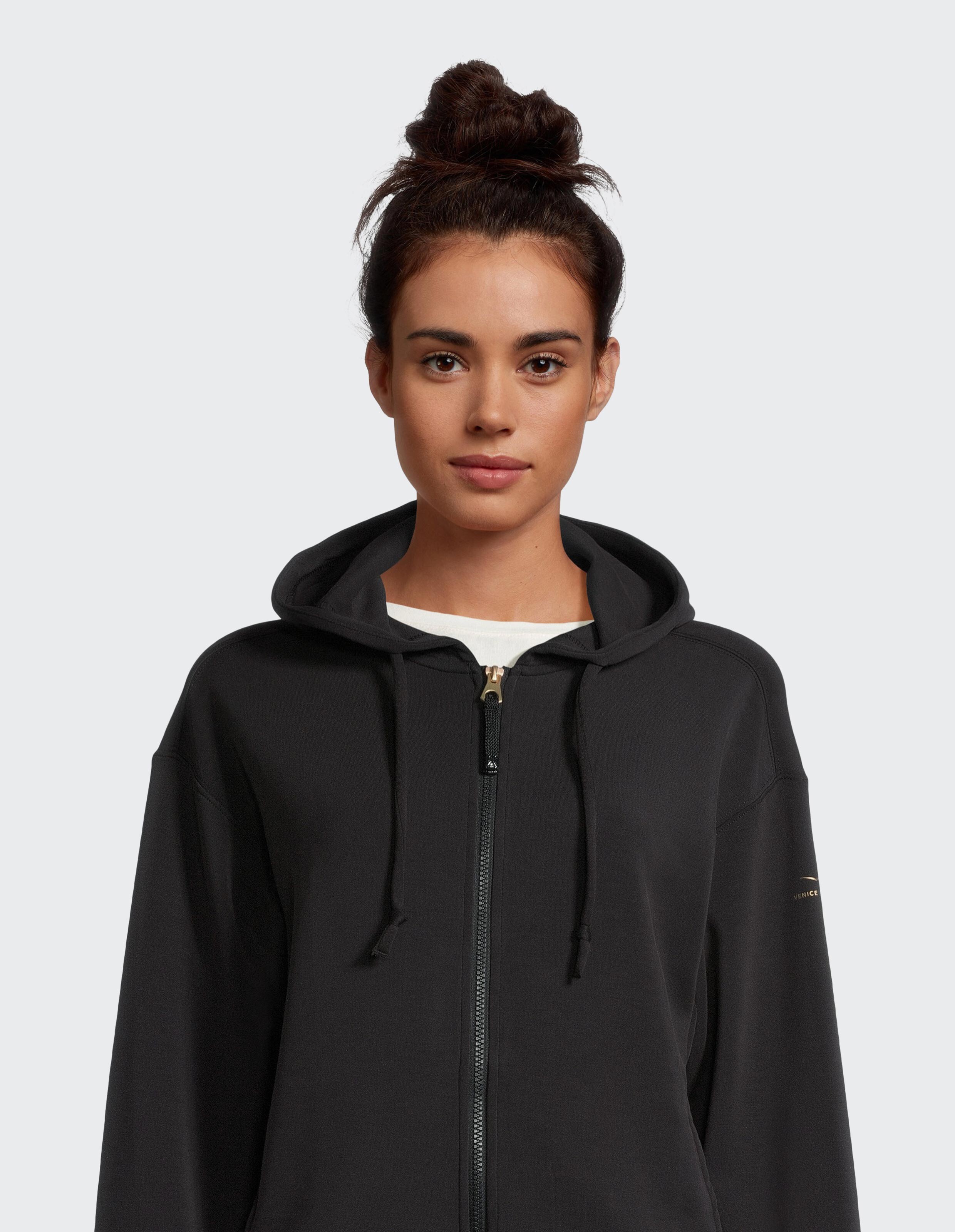 Frau trägt einen kuscheligen schwarzen Kapuzenpullover mit Reißverschluss, perfekt für lässige Loungewear.