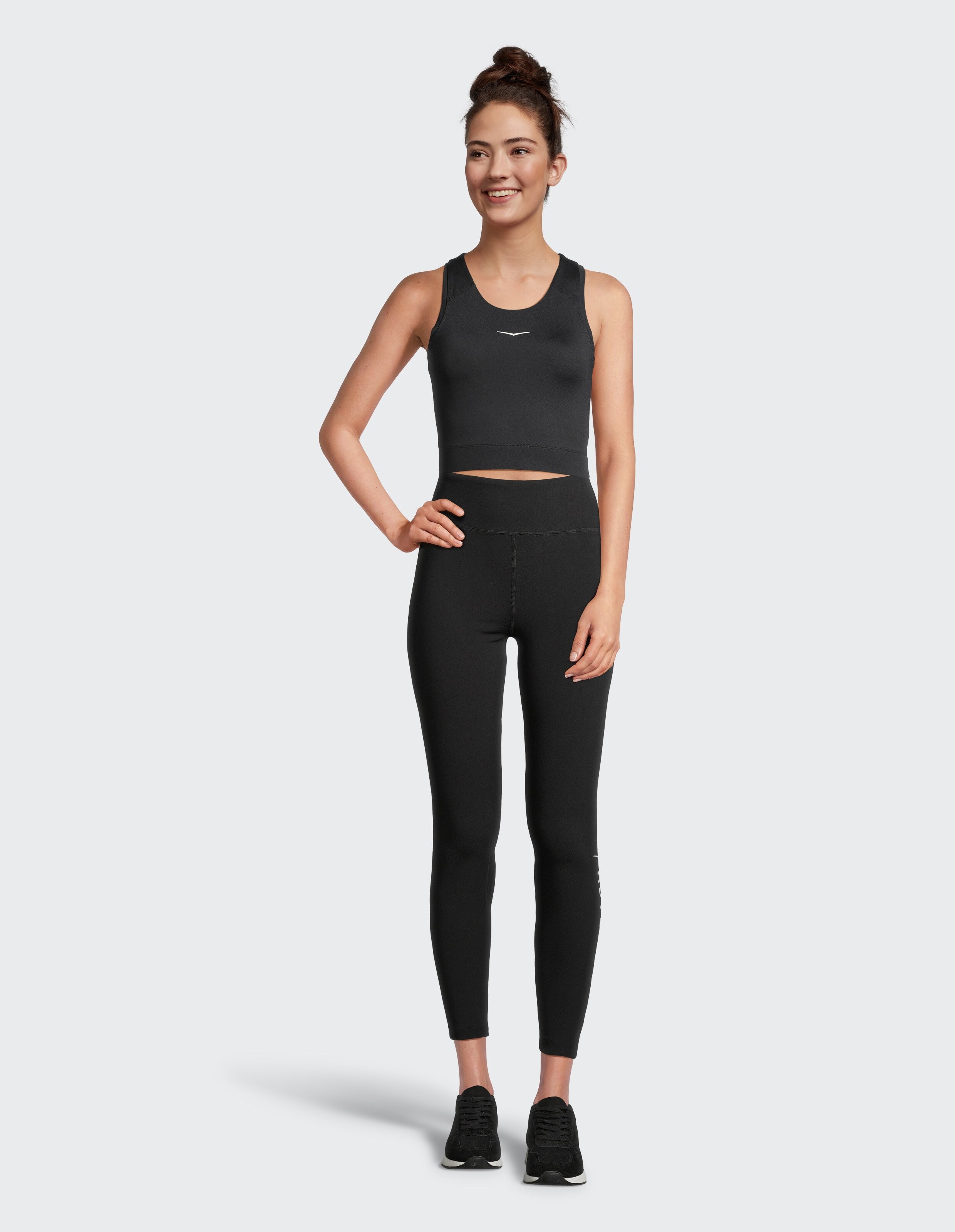 Das Model trägt ein schwarzes, kurzes Tanktop und passende Leggings, perfekt für Freizeitkleidung.