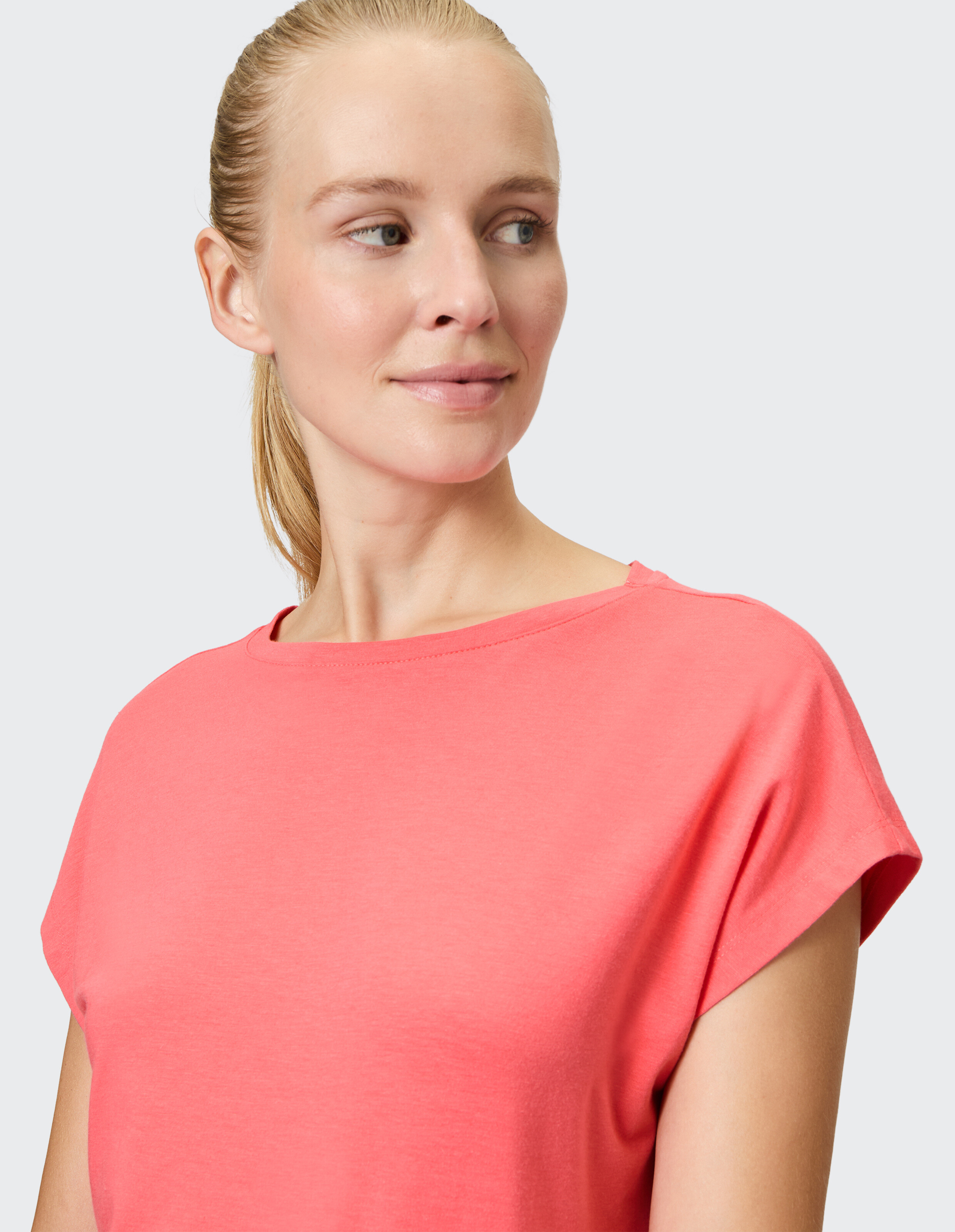Frau trägt ein gemütliches, korallenfarbenes Freizeit-T-Shirt für bequemen Alltagsstil.