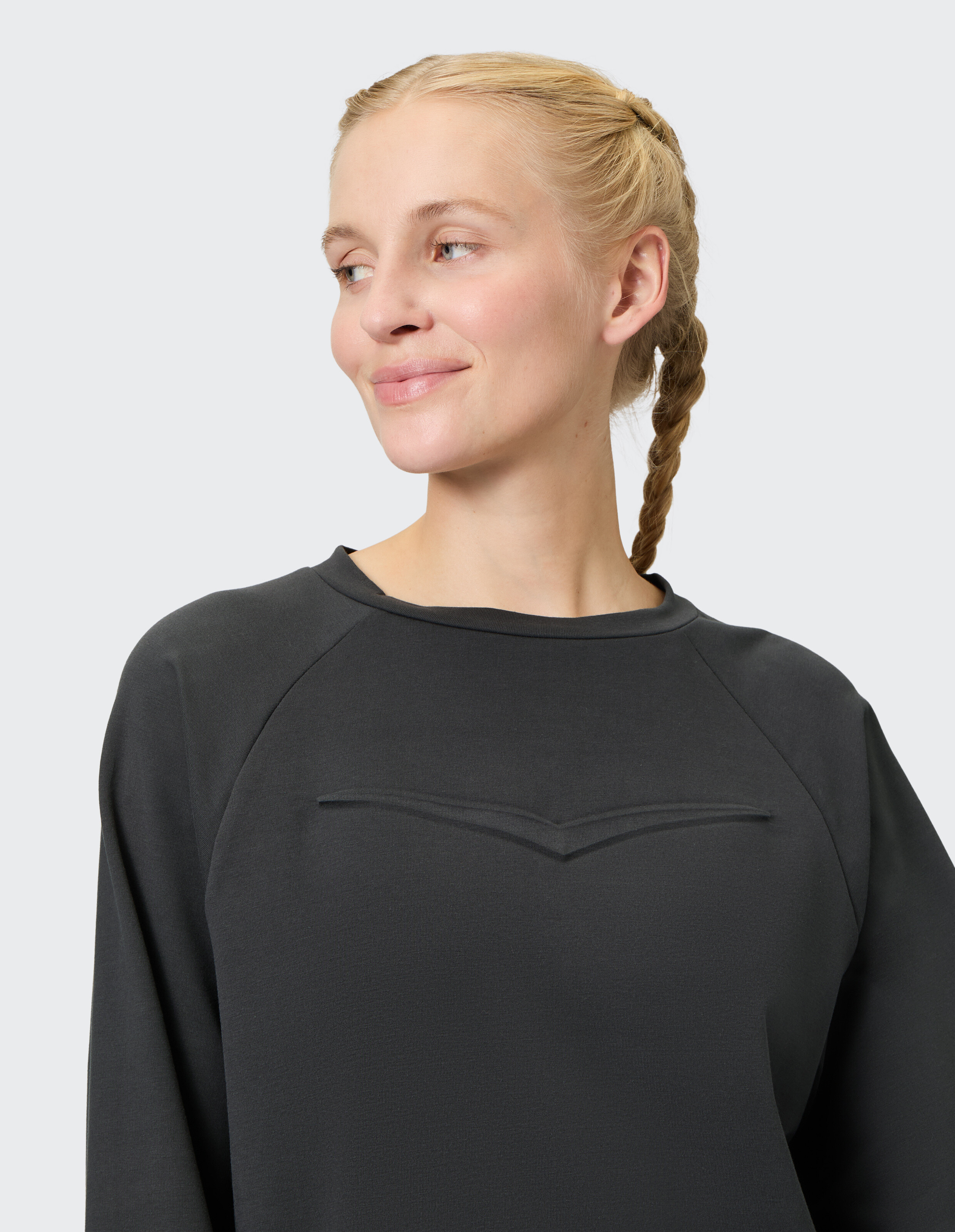 Frau trägt ein gemütliches dunkelgraues Freizeit-Sweatshirt mit dekorativer Brustnaht.