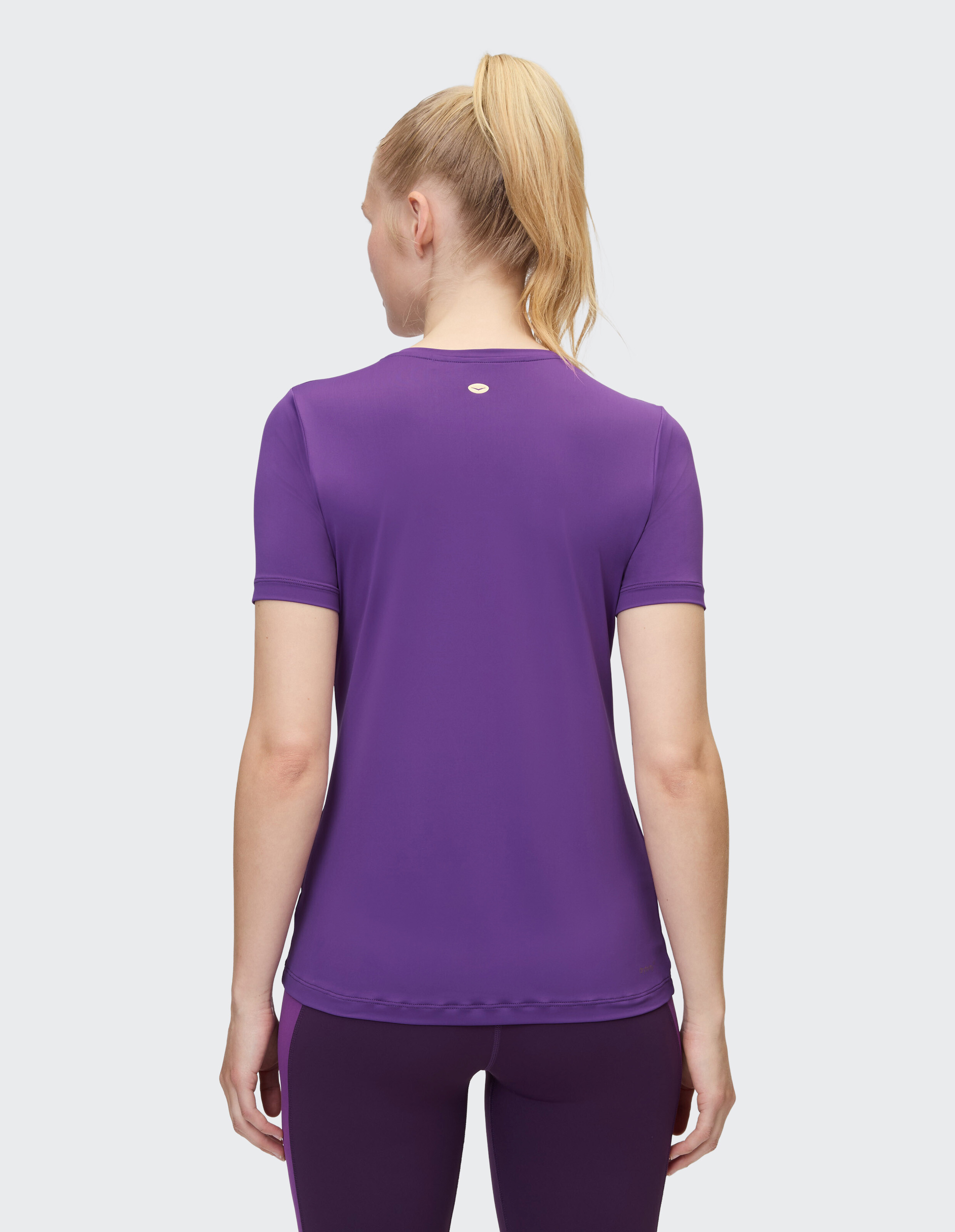 Frau trägt ein lila kurzärmeliges Freizeit-T-Shirt, Rückansicht, Studioumgebung.