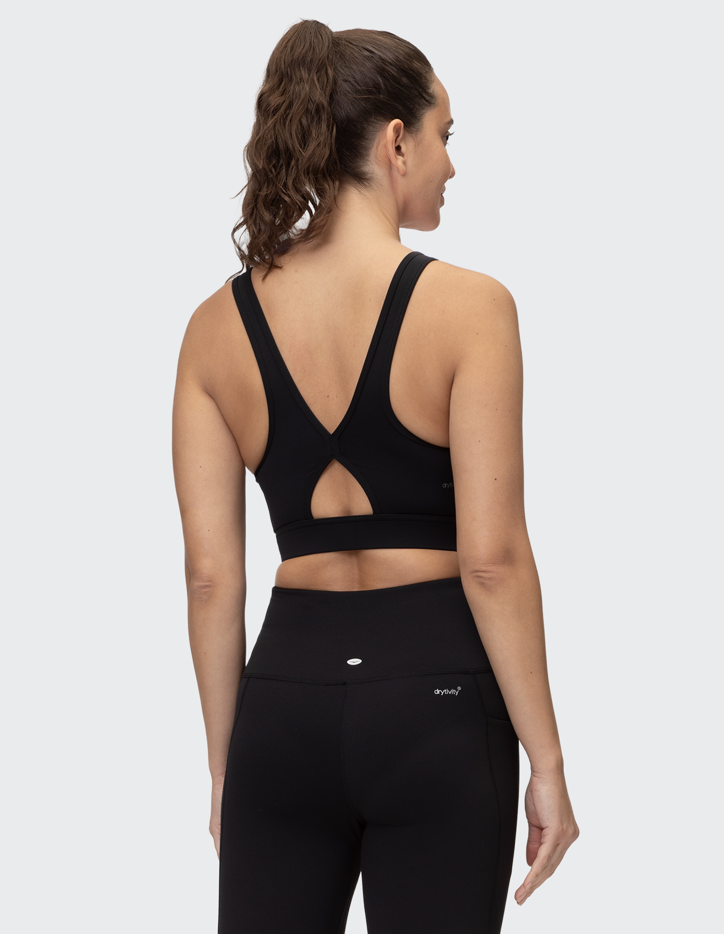 Rückansicht einer Frau in einem schwarzen Sport-BH und Leggings, die einen stilvollen Schnitt zeigt.