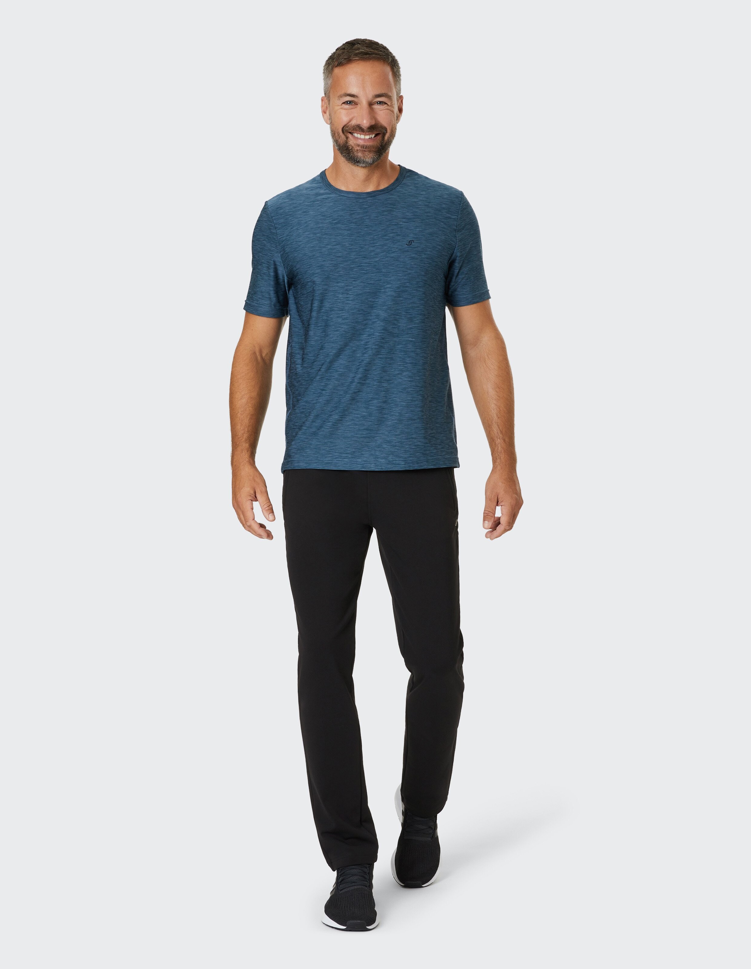 Mann trägt ein blau meliertes T-Shirt und eine schwarze Freizeithose für einen bequemen Look.