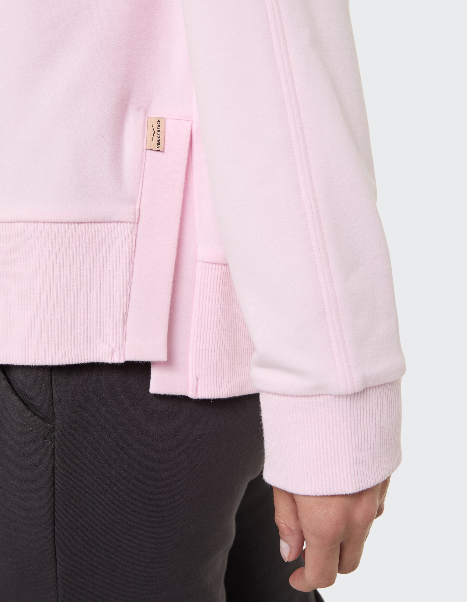 Nahaufnahme eines rosa lässigen Sweatshirts mit gerippten Bündchen und Seitendetails.