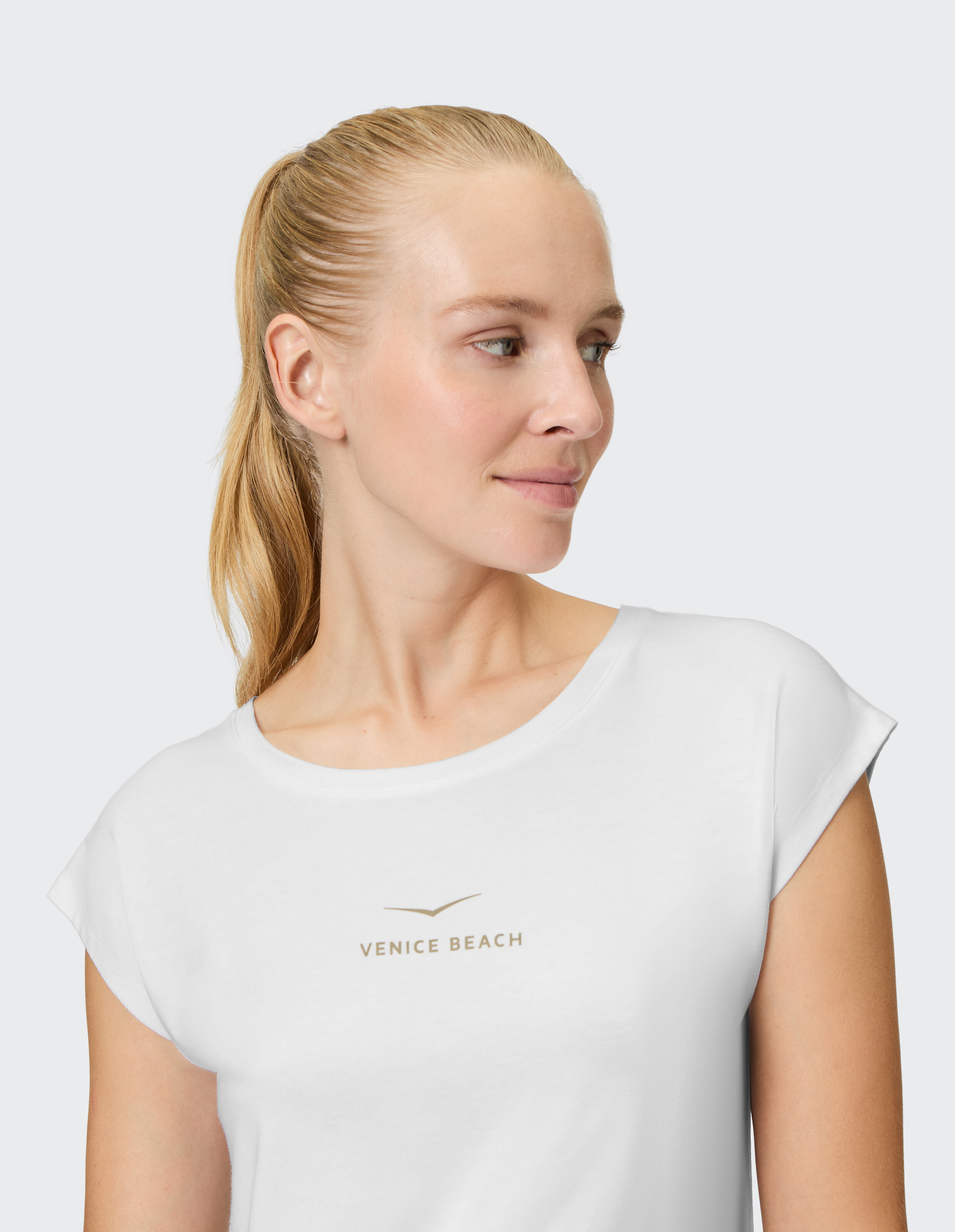 Frau trägt ein weißes, lässiges T-Shirt mit Venice Beach-Logo für bequeme Loungewear.