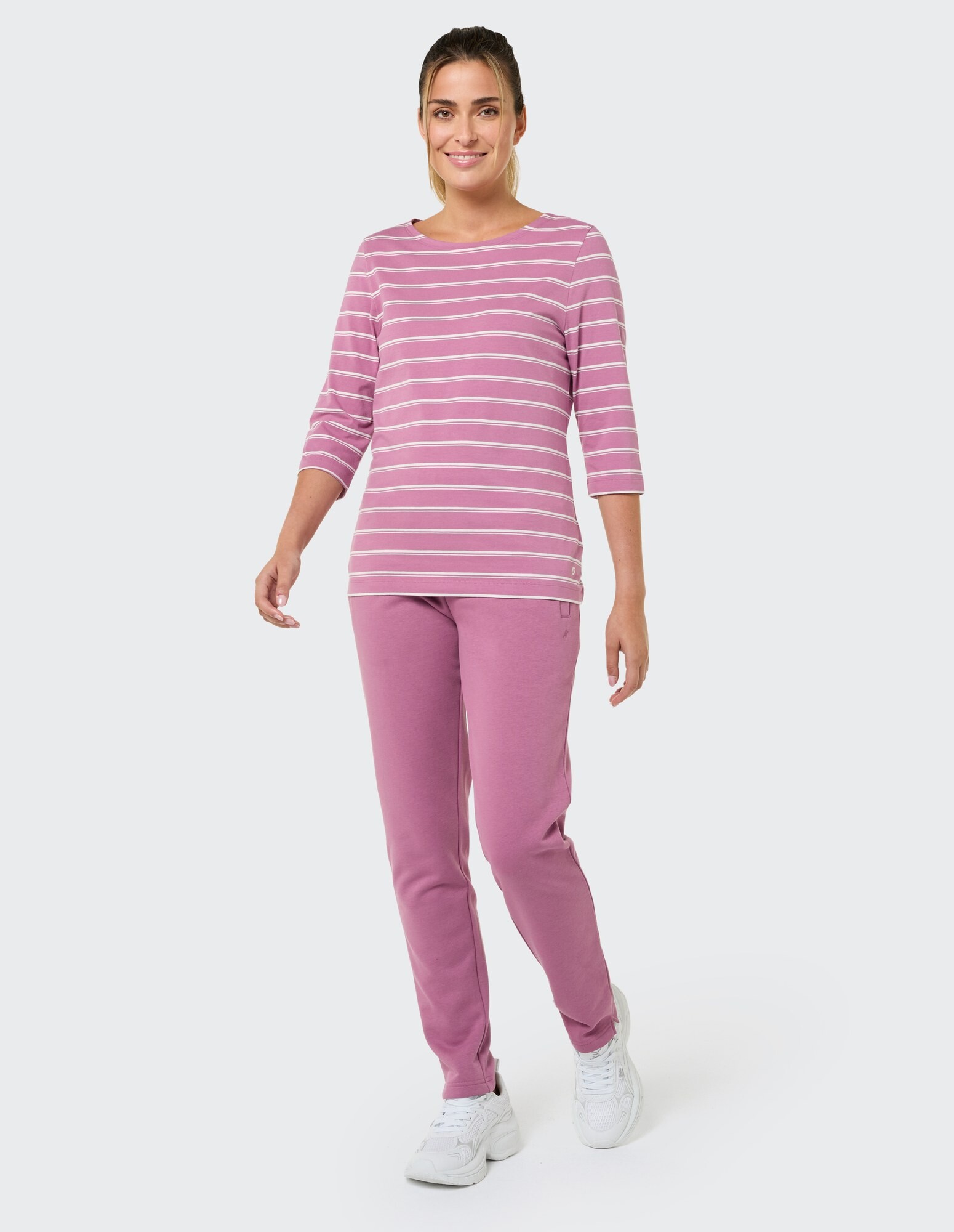 Frau in rosa gestreiftem Oberteil und passender Hose, perfekt für Freizeitkleidung.