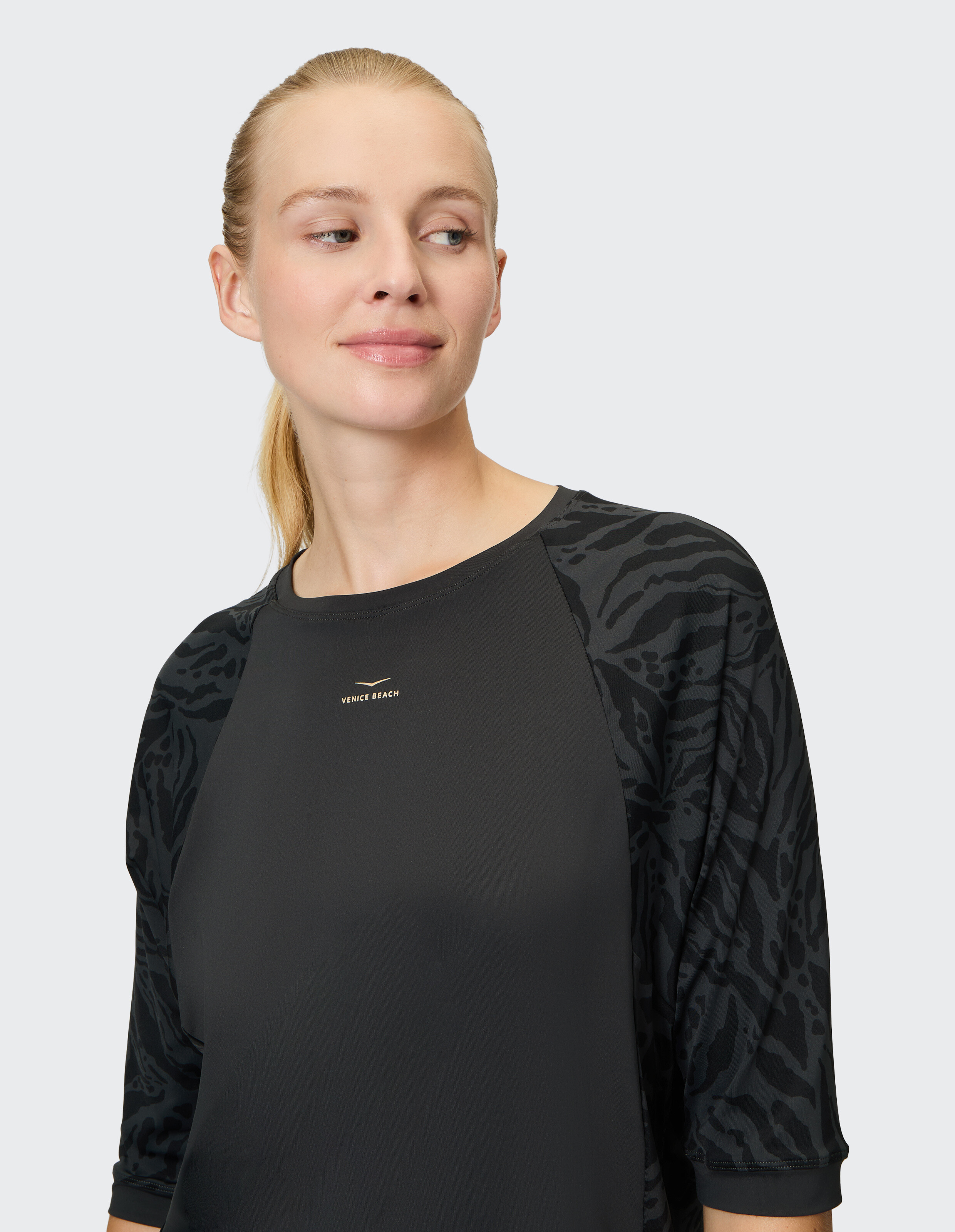 Frau in einem stilvollen schwarzen Top mit gemusterten Ärmeln, perfekt für Freizeitkleidung.