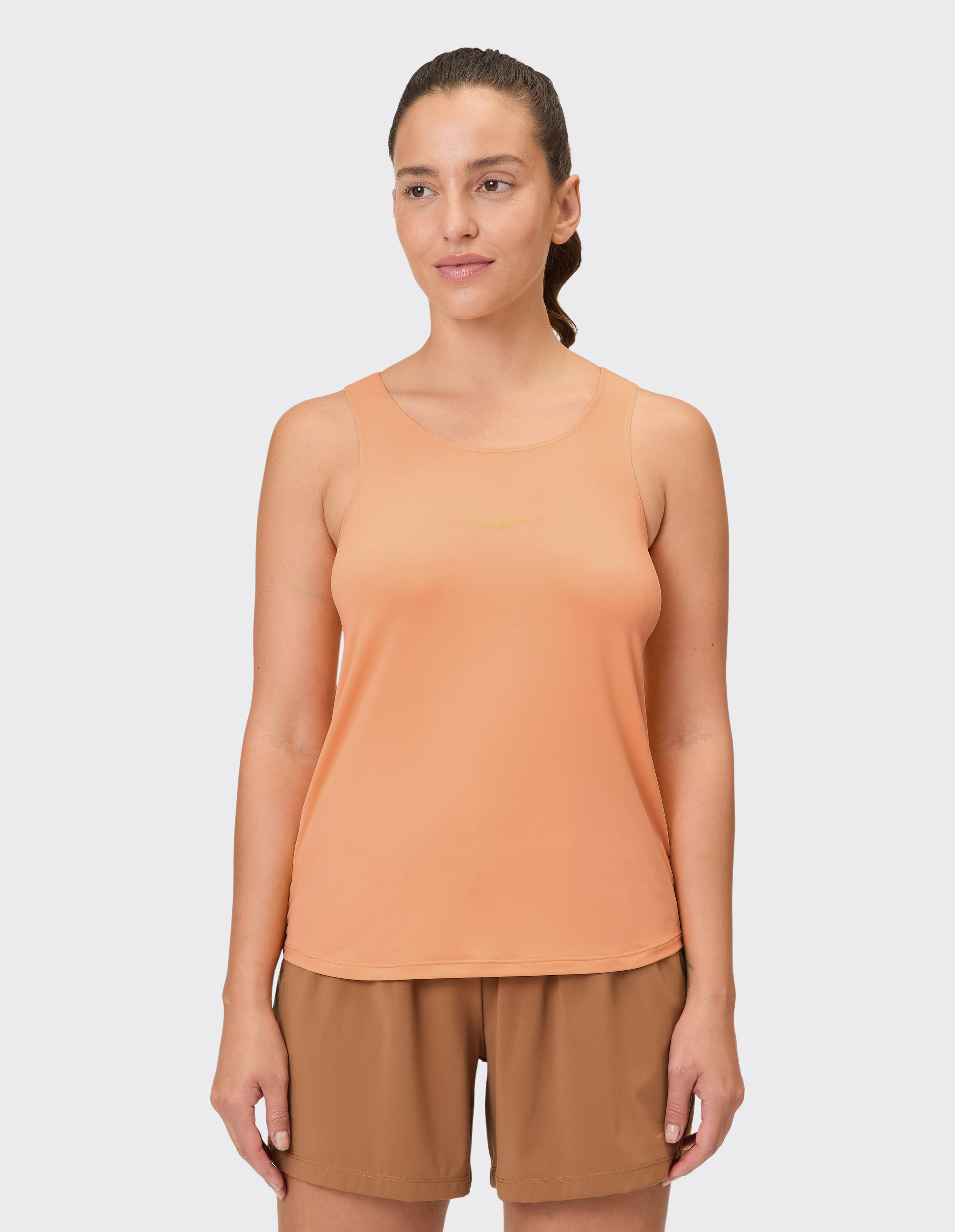 Frau trägt ein pfirsichfarbenes Tanktop und braune Shorts, perfekt für Freizeitkleidung.