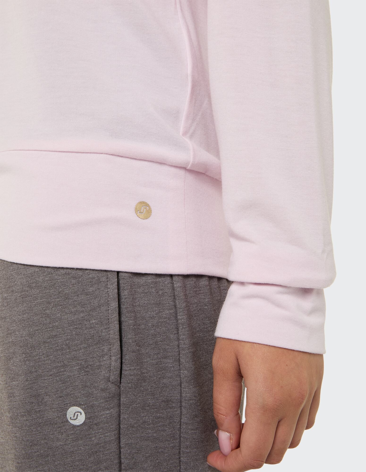 Nahaufnahme eines hellrosa Langarmhemds gepaart mit einer grauen Loungehose.