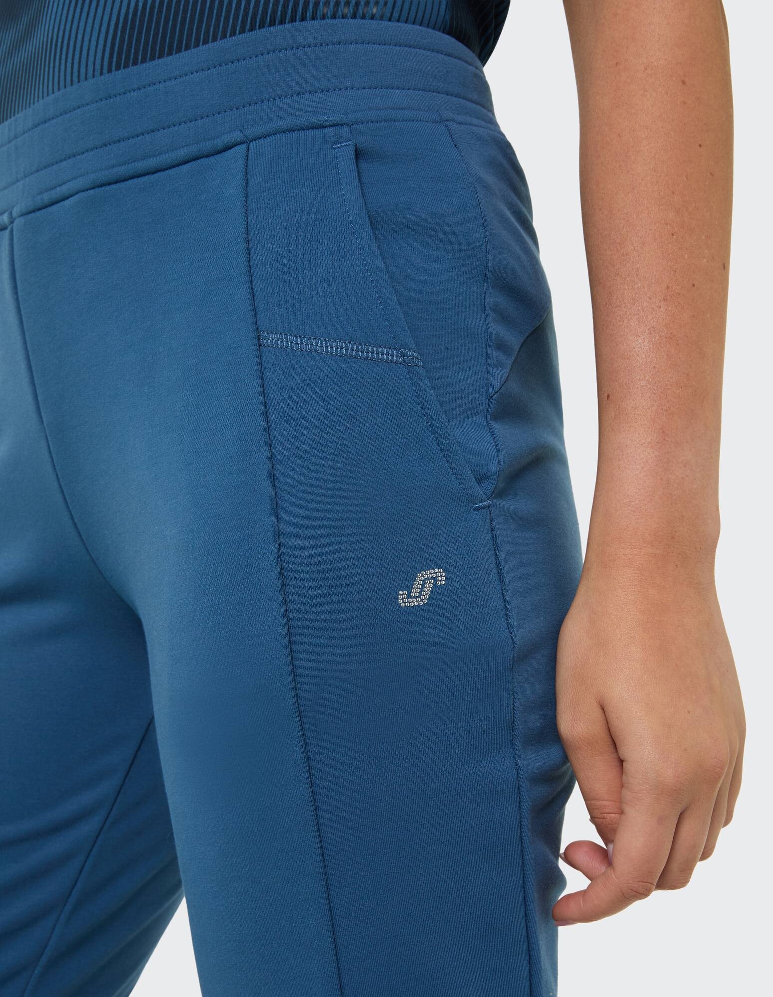 Nahaufnahme einer blauen Freizeit-Jogginghose mit Seitentaschen und Logo-Detail.