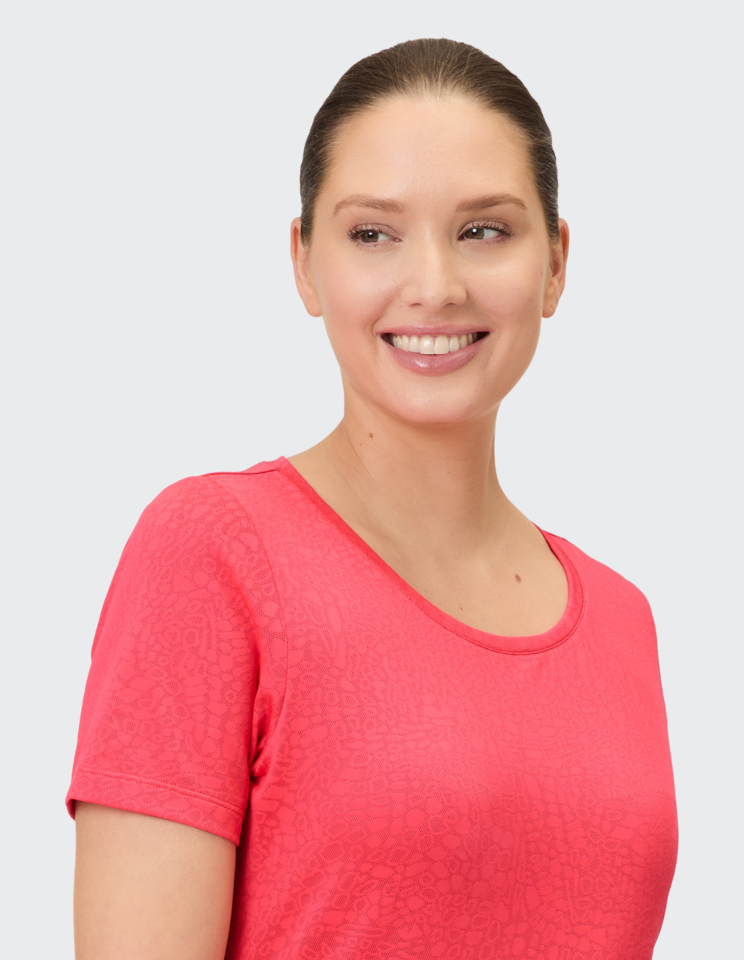 Lächelnde Frau in einem rosa lässigen T-Shirt mit Strukturmuster.