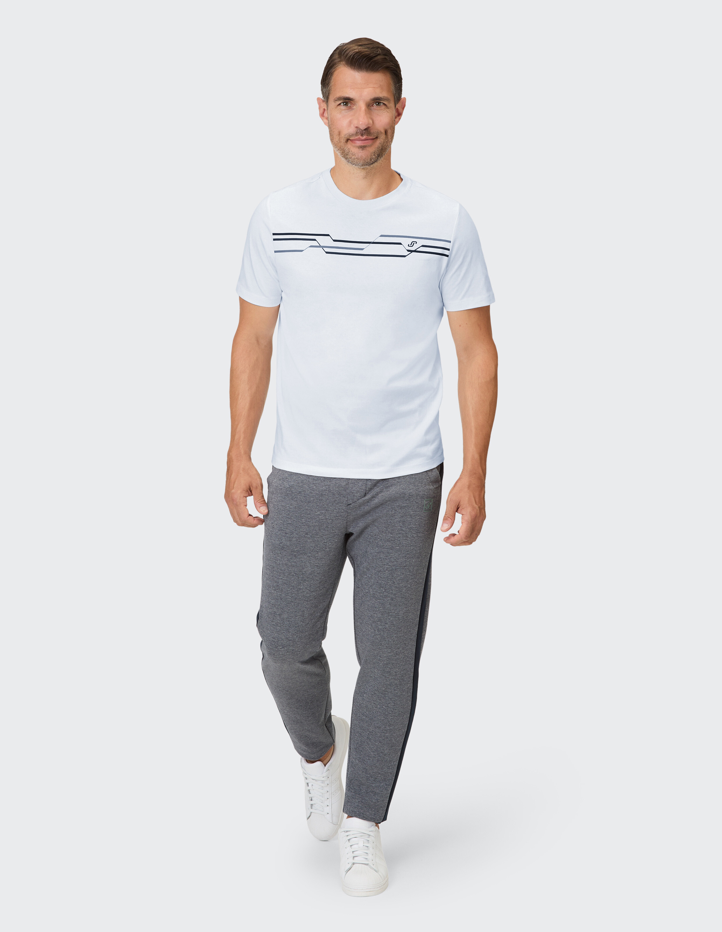 Mann in einem weiß gestreiften T-Shirt und grauen Jogginghosen, perfekt für Freizeitkleidung.