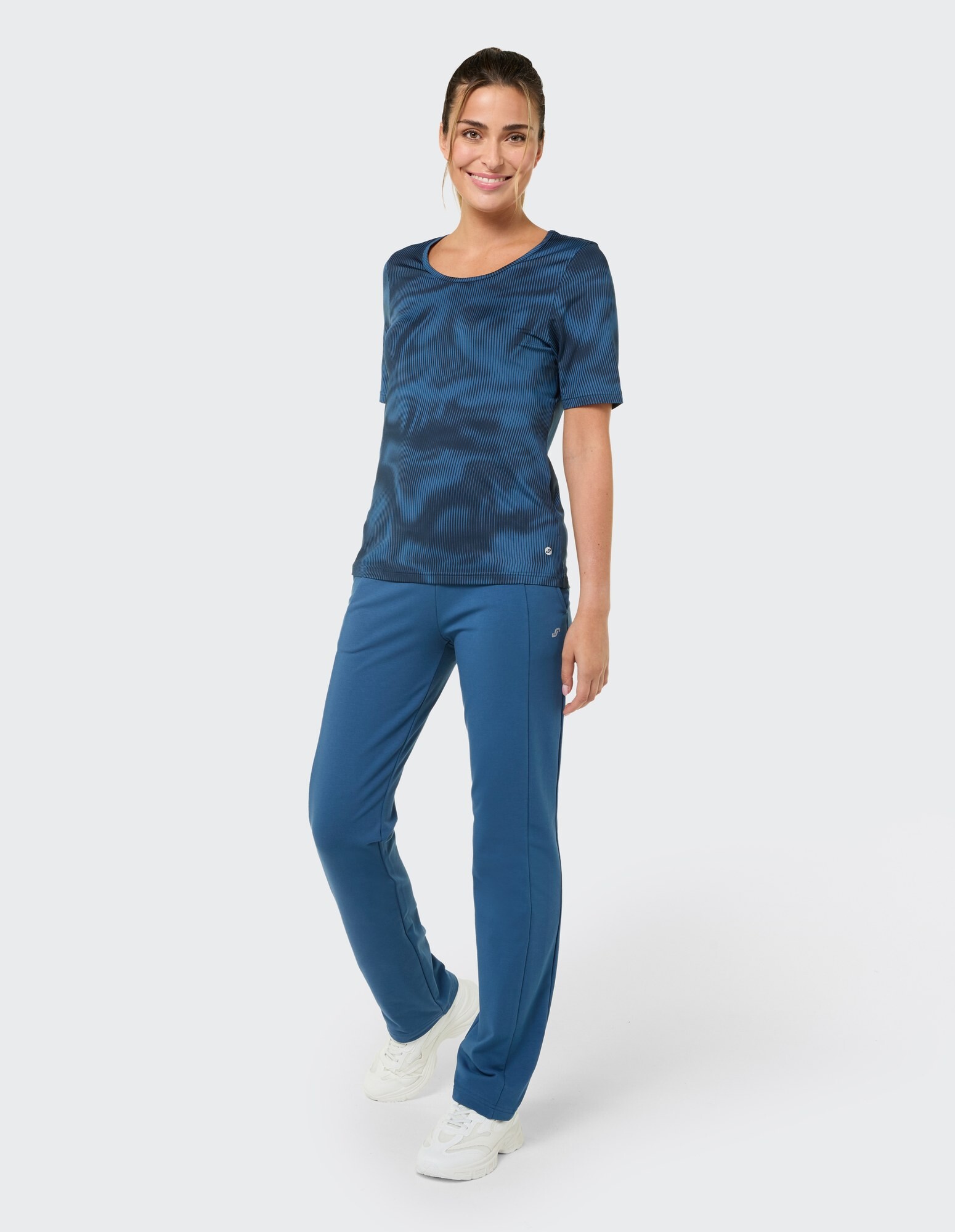 Frau in einem stilvollen blauen Freizeitoutfit mit strukturiertem Oberteil und passender Hose.