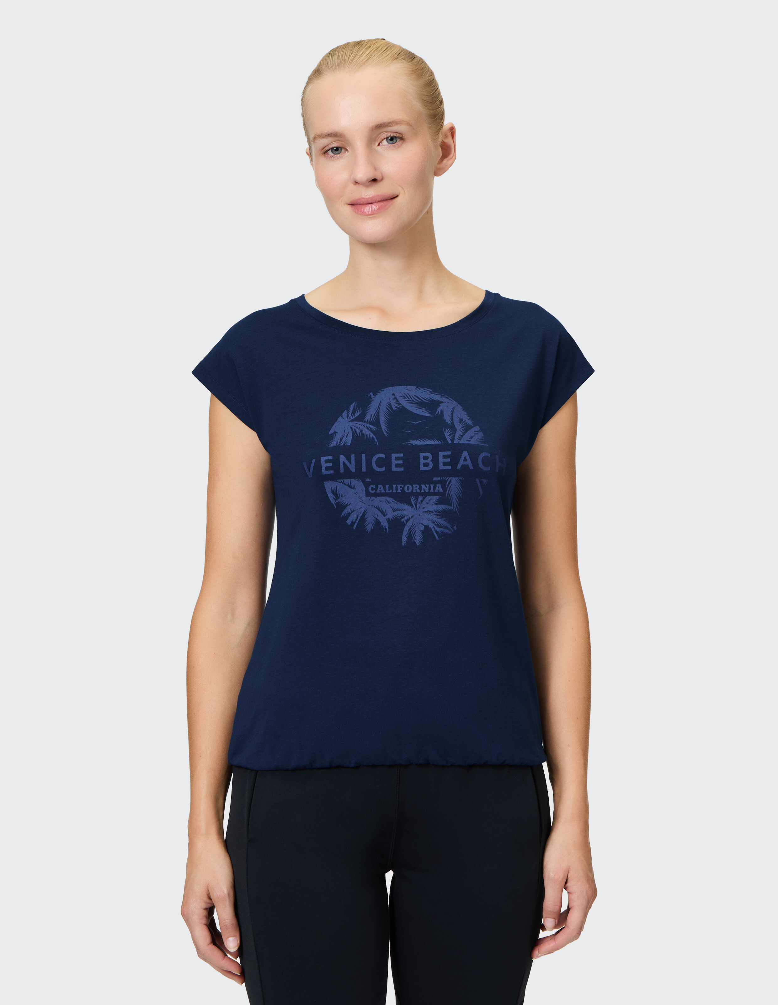 Frau trägt ein marineblaues Freizeit-T-Shirt mit Venice Beach-Grafikdruck.