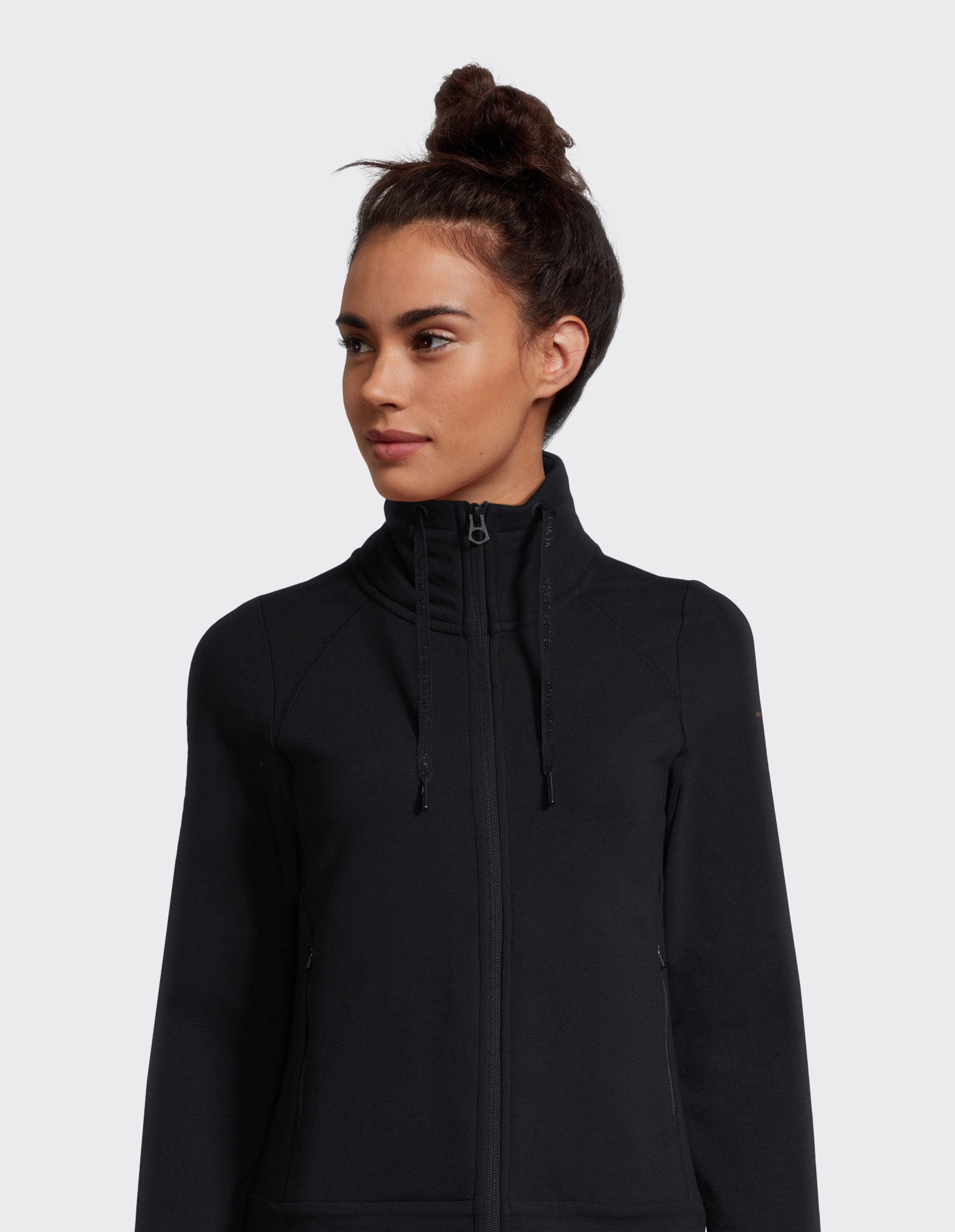 Frau trägt eine schwarze ELBSAND-Reißverschlussjacke mit hohem Kragen für gemütlichen Casual-Style.
