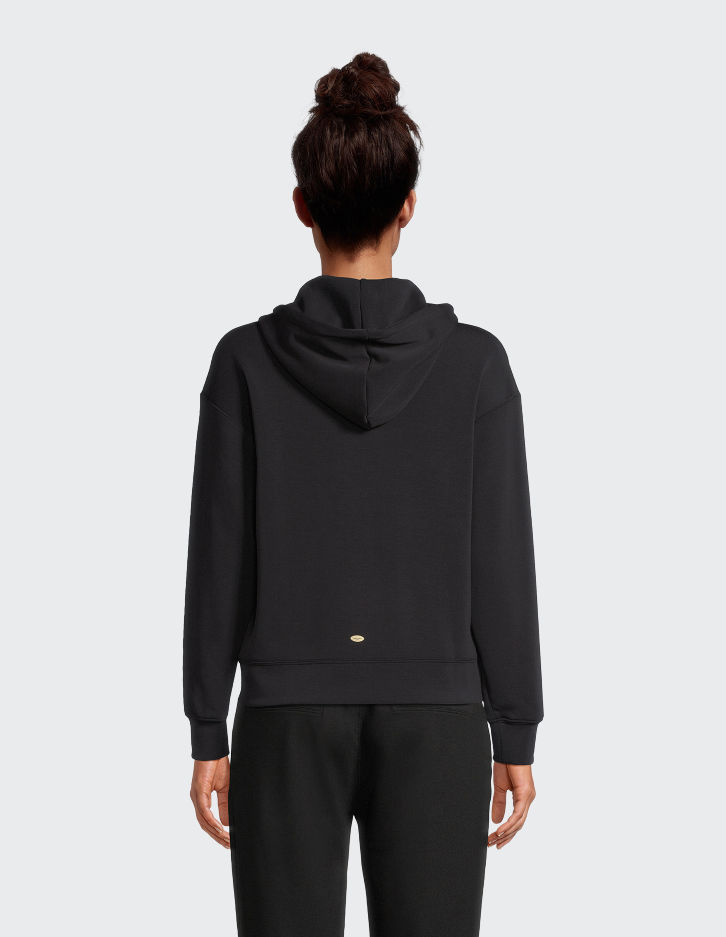 Rückansicht einer Frau, die einen kuscheligen schwarzen ELBSAND-Hoodie für lässige Loungewear trägt.