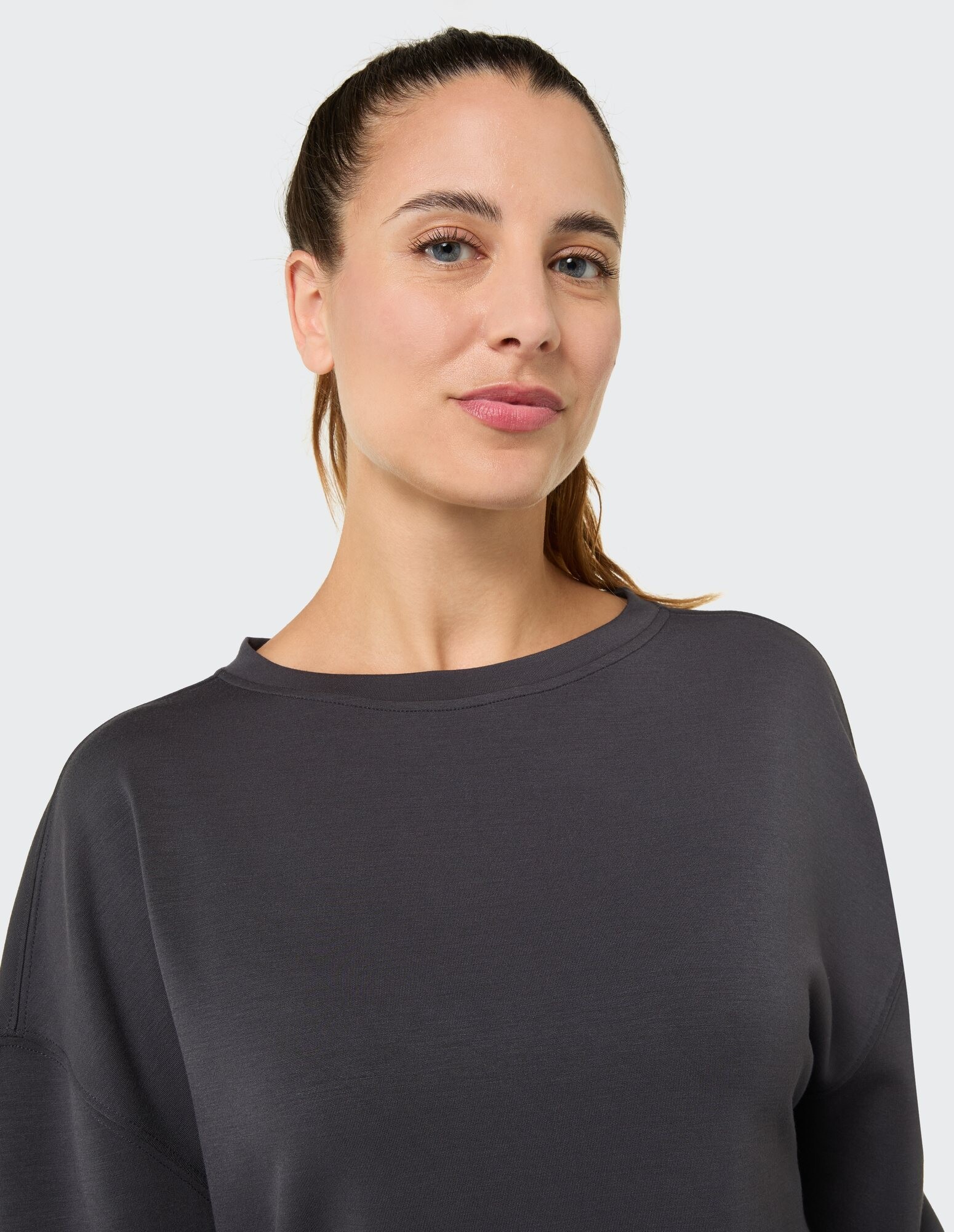 Nahaufnahme einer Frau in einem dunkelgrauen Freizeit-Sweatshirt mit entspannter Passform.