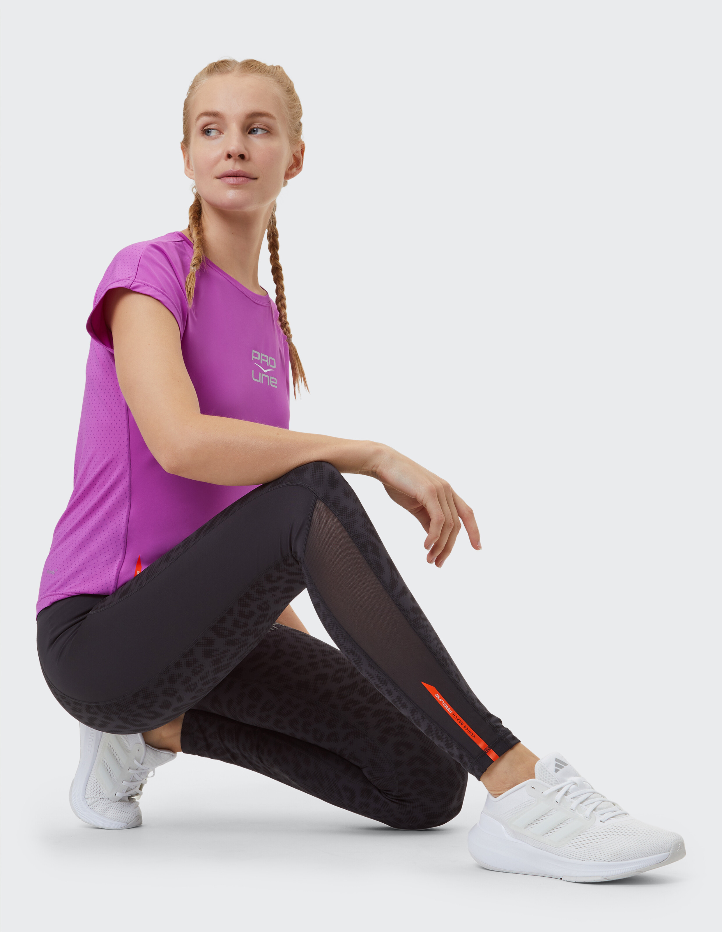 Frau trägt ein lila Sporthemd und schwarze Leggings mit Leopardenmuster für lässige Fitness.
