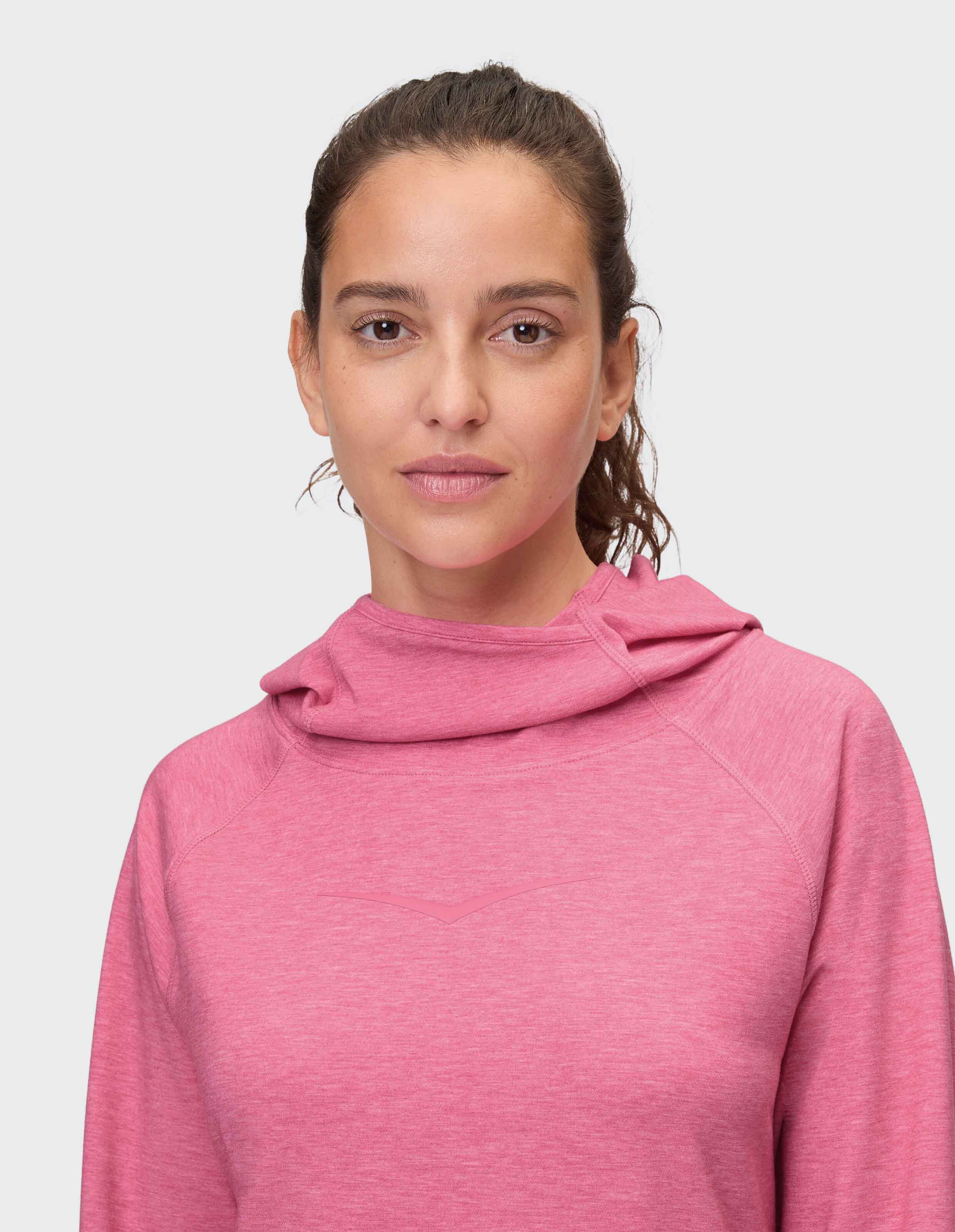 Frau trägt einen kuscheligen rosa Kapuzenpullover mit entspannter Passform und weichem Stoff.