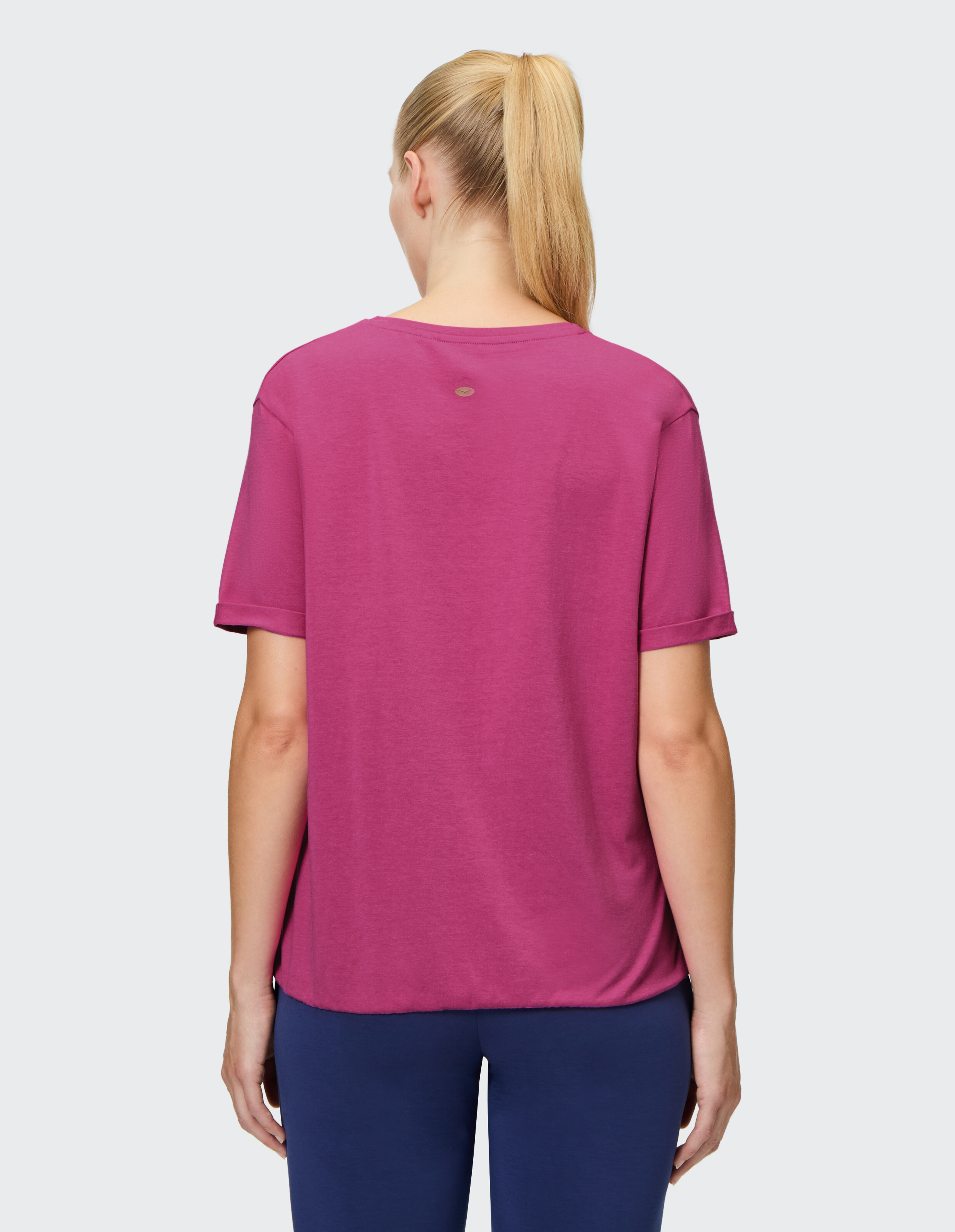 Rückansicht einer Frau, die ein gemütliches rosa Freizeit-T-Shirt mit kurzen Ärmeln trägt.