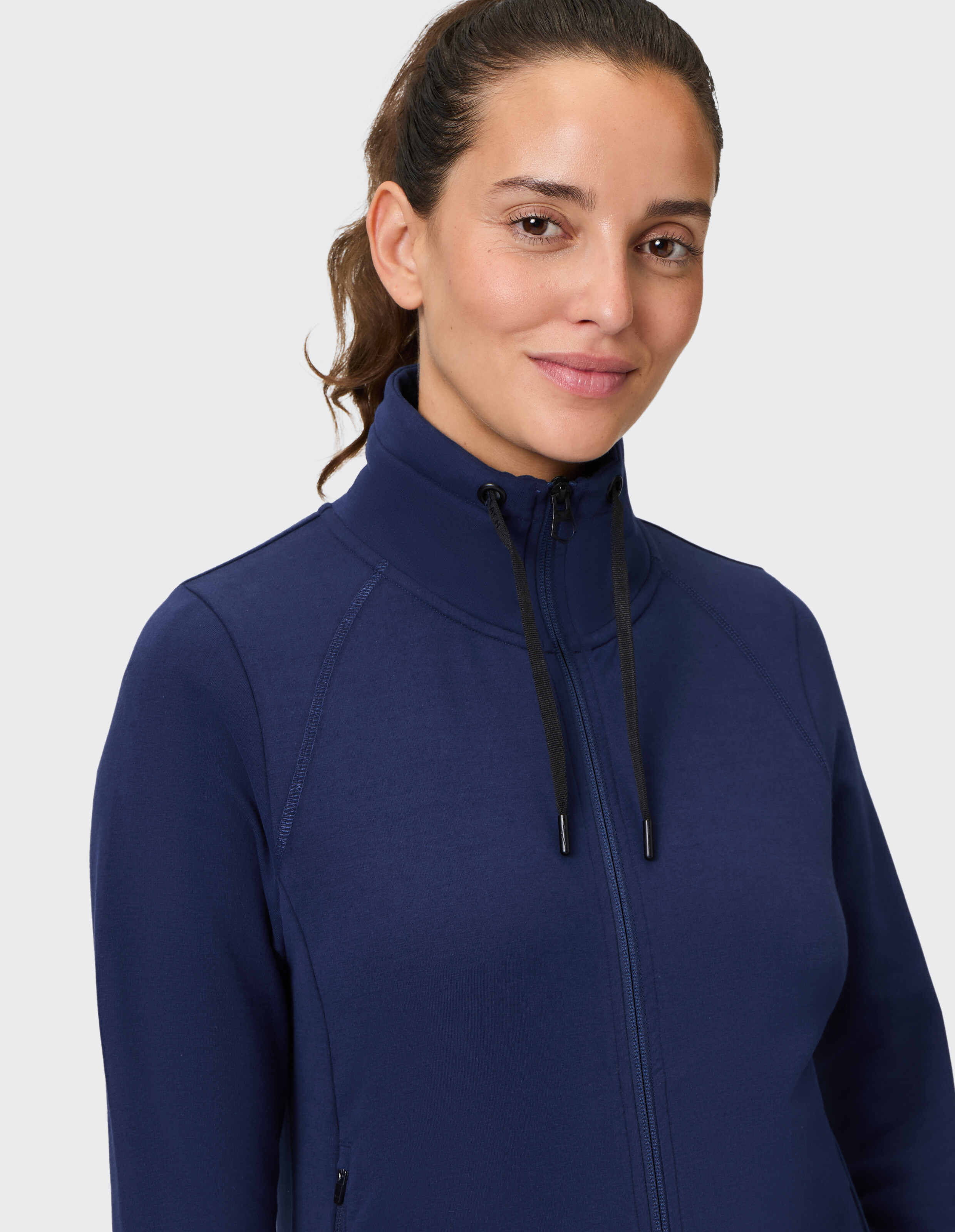 Frau trägt ein dunkelblaues Sweatshirt mit Reißverschluss, hohem Kragen und Kordelzug.