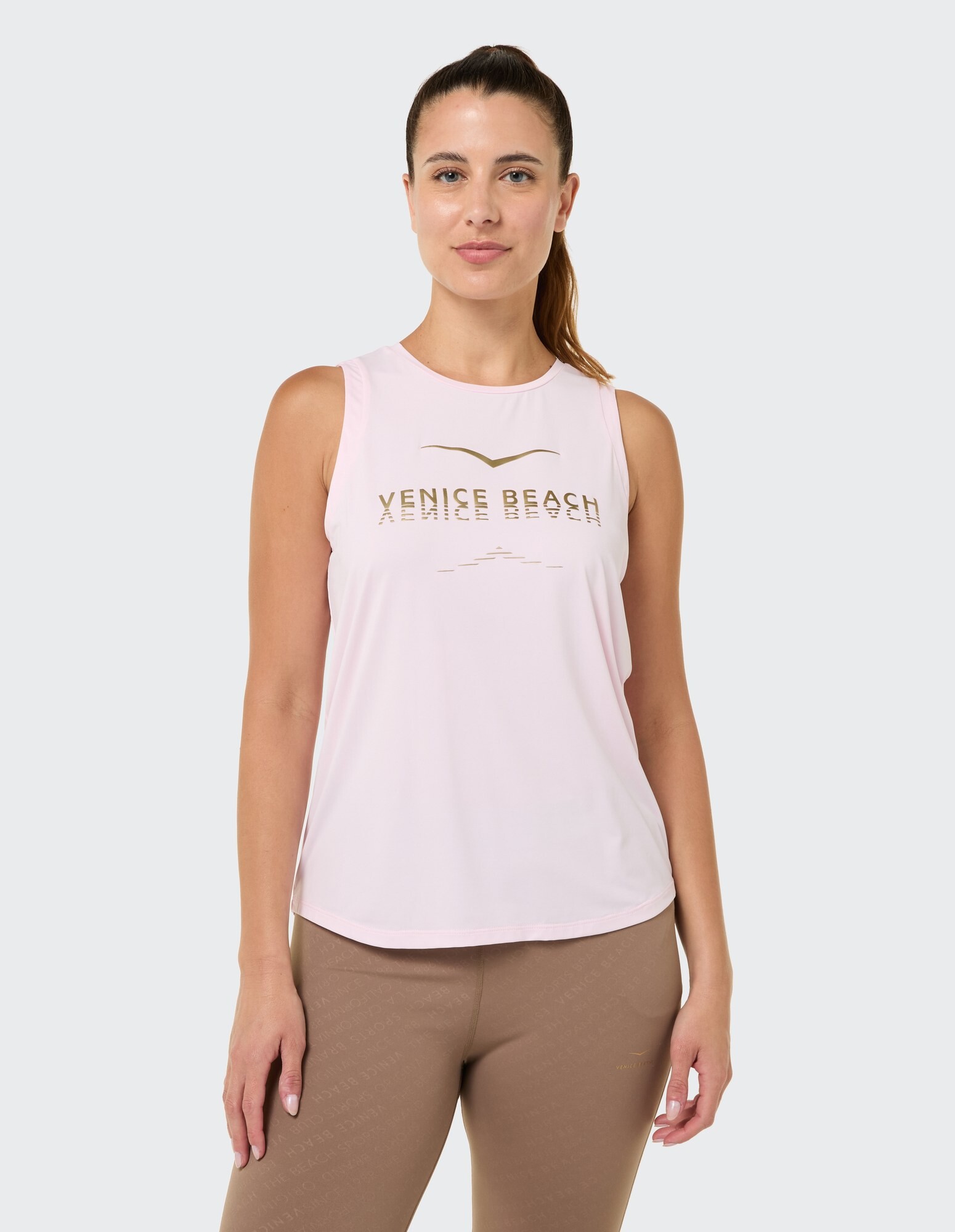 Hellrosa ärmelloses Oberteil mit „Venice Beach“-Grafik, gepaart mit braunen Leggings.