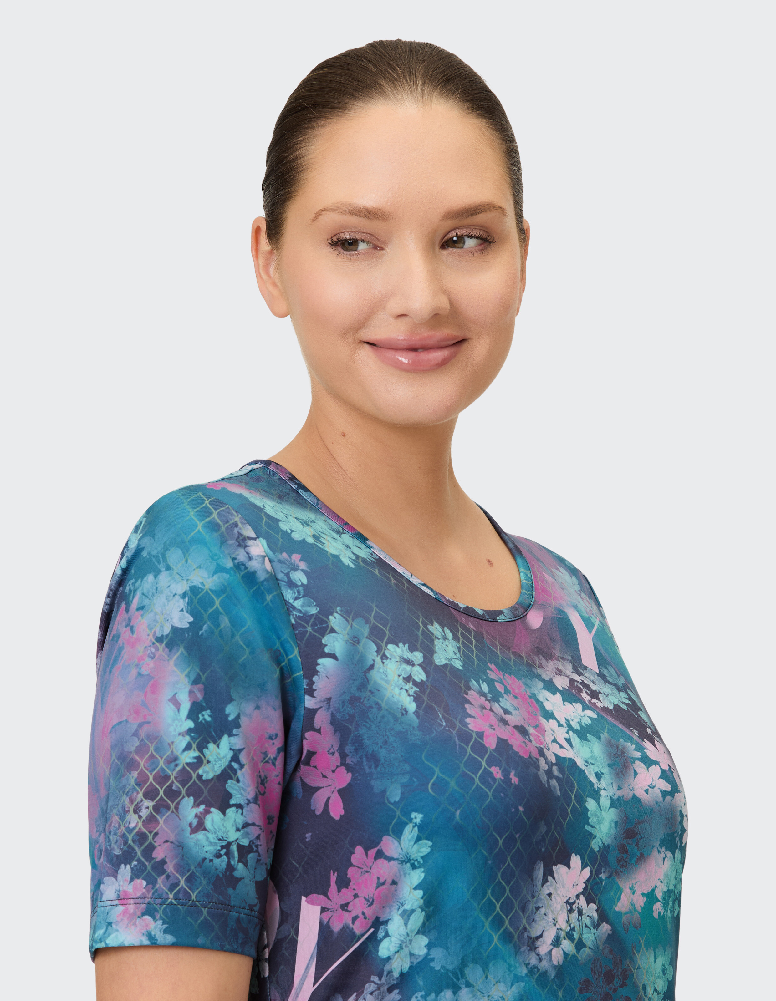 Nahaufnahme einer Frau in einem farbenfrohen, lässigen Oberteil mit Blumenmuster und kurzen Ärmeln.