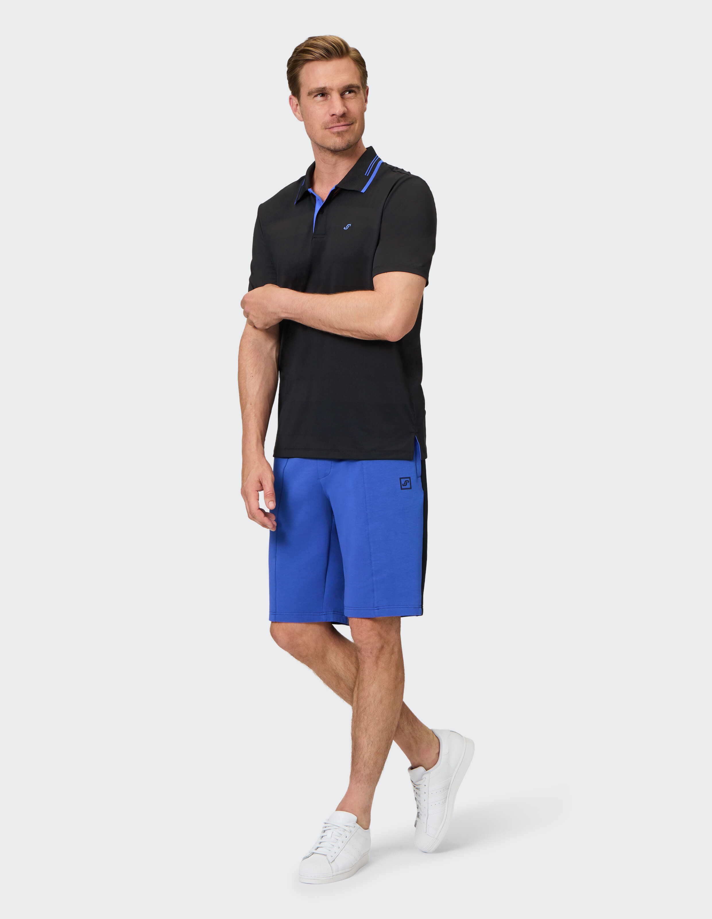 Mann trägt ein schwarzes Poloshirt und blaue Freizeitshorts für einen stilvollen, bequemen Look.