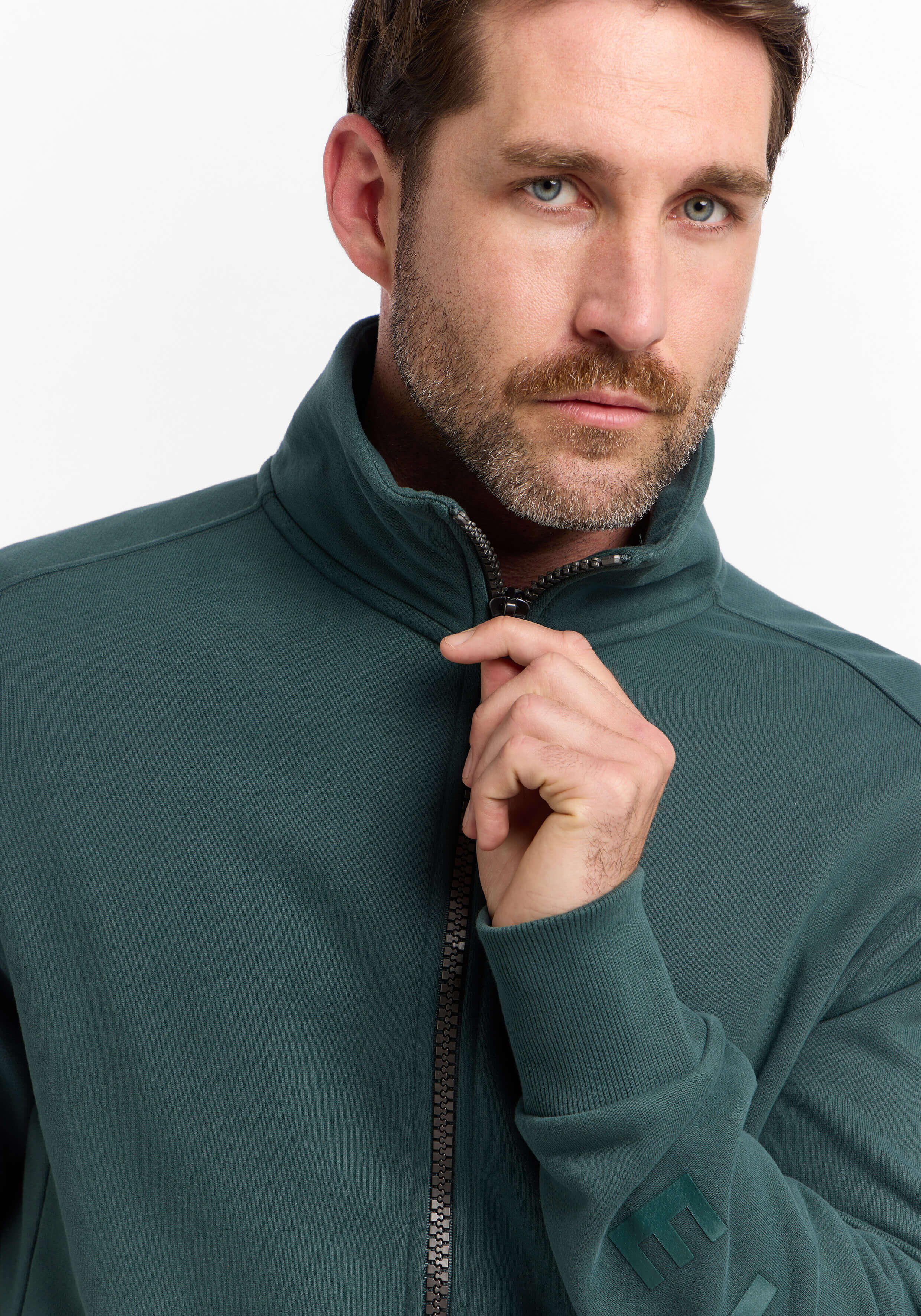 Mann trägt ein gemütliches dunkelgrünes Sweatshirt mit Reißverschluss und hohem Kragen für lässigen Stil.