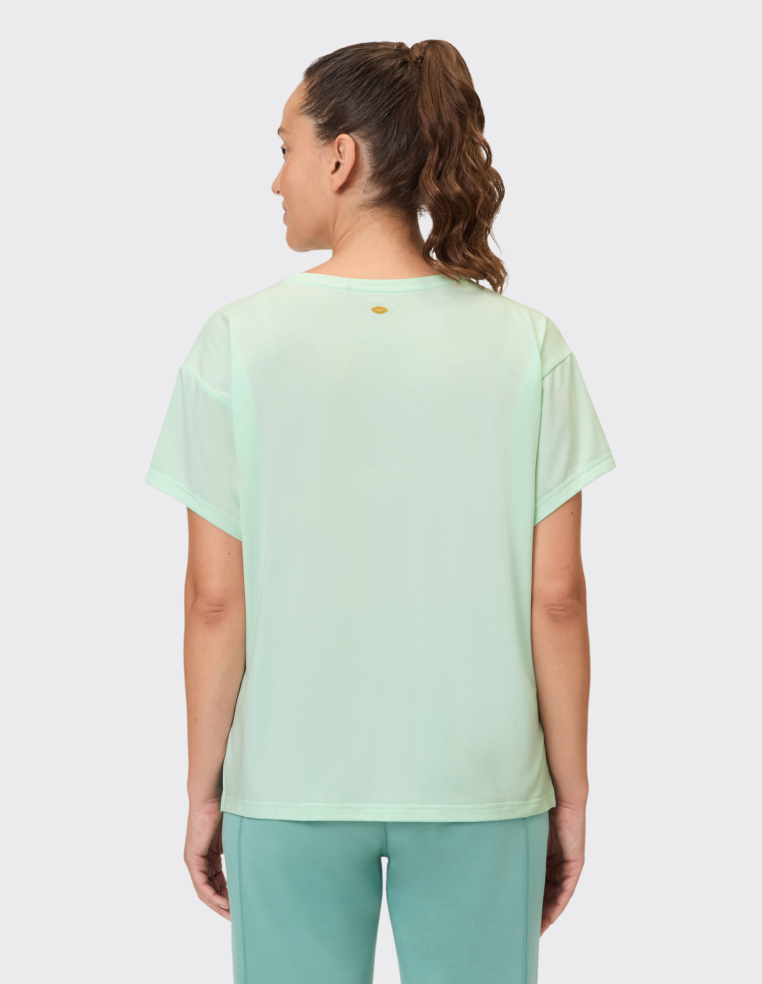 Frau trägt ein hellgrünes Freizeit-T-Shirt, Rückansicht, perfekt für bequeme Loungewear.