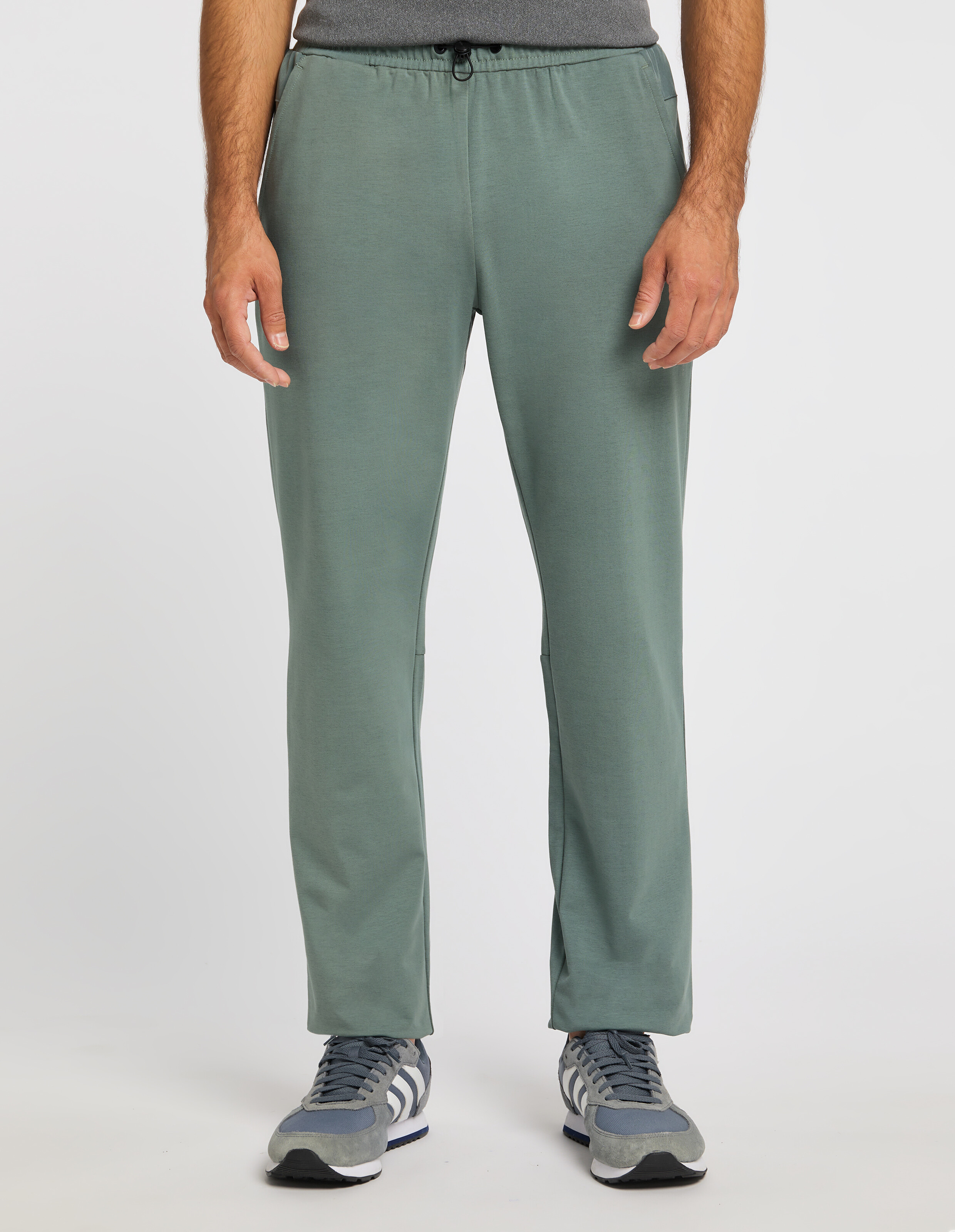 Mann trägt salbeigrüne, lässige Lounge-Hose mit elastischem Kordelzug in der Taille.