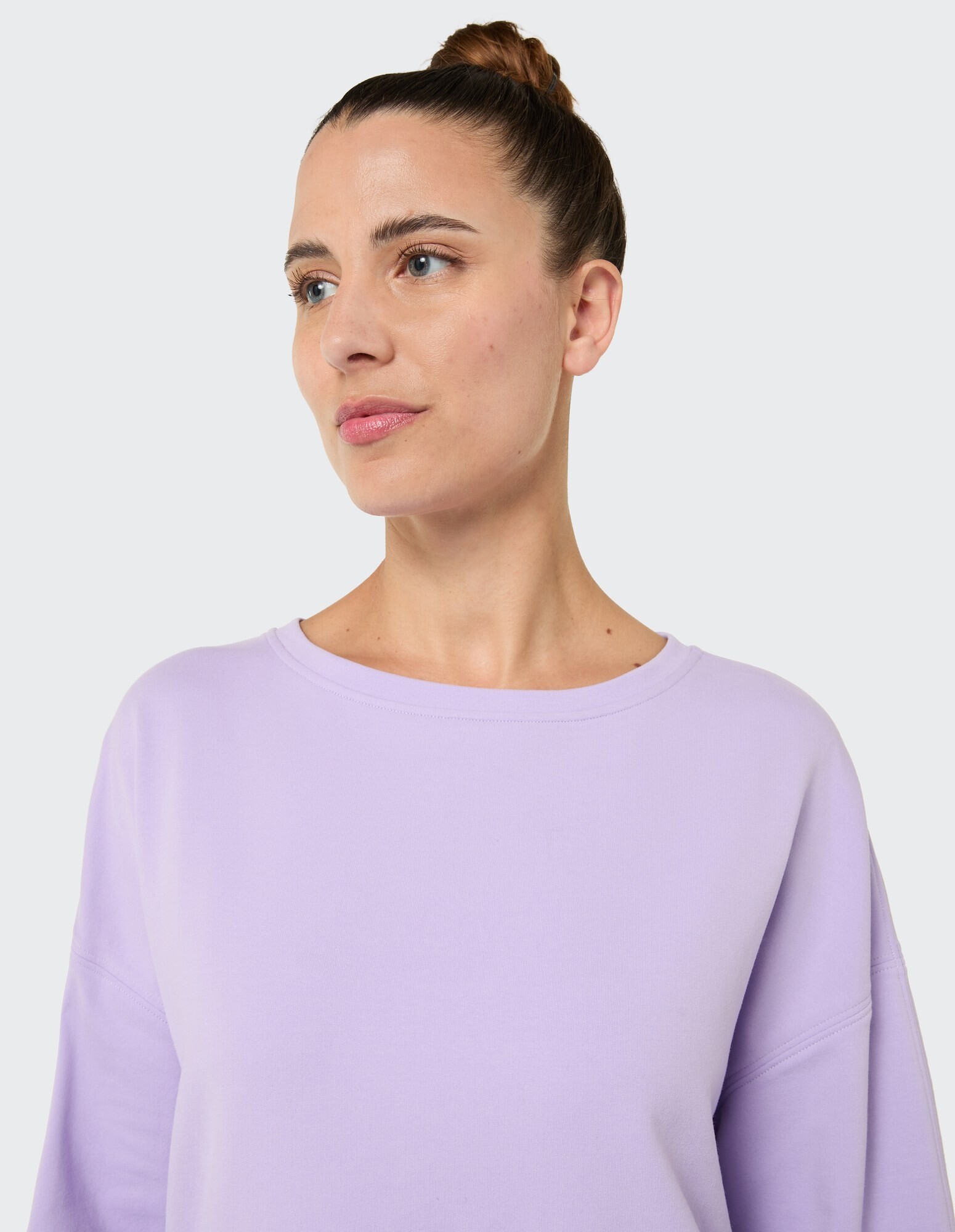 Das Model trägt ein gemütliches lavendelfarbenes Sweatshirt mit entspannter Passform und weitem Ausschnitt.