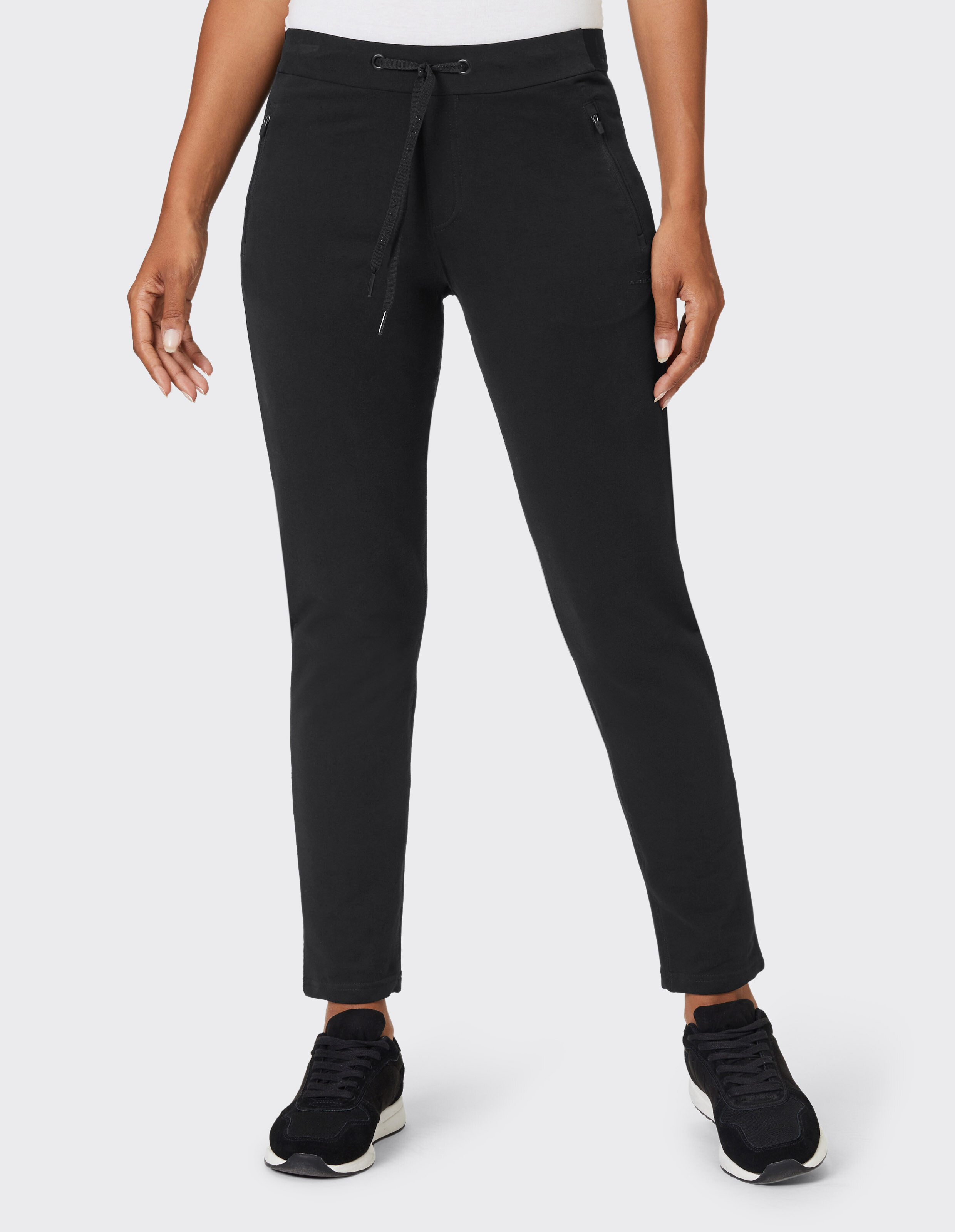 Frau trägt eine schwarze, lässige Loungehose mit Kordelzug in der Taille und Seitentaschen.