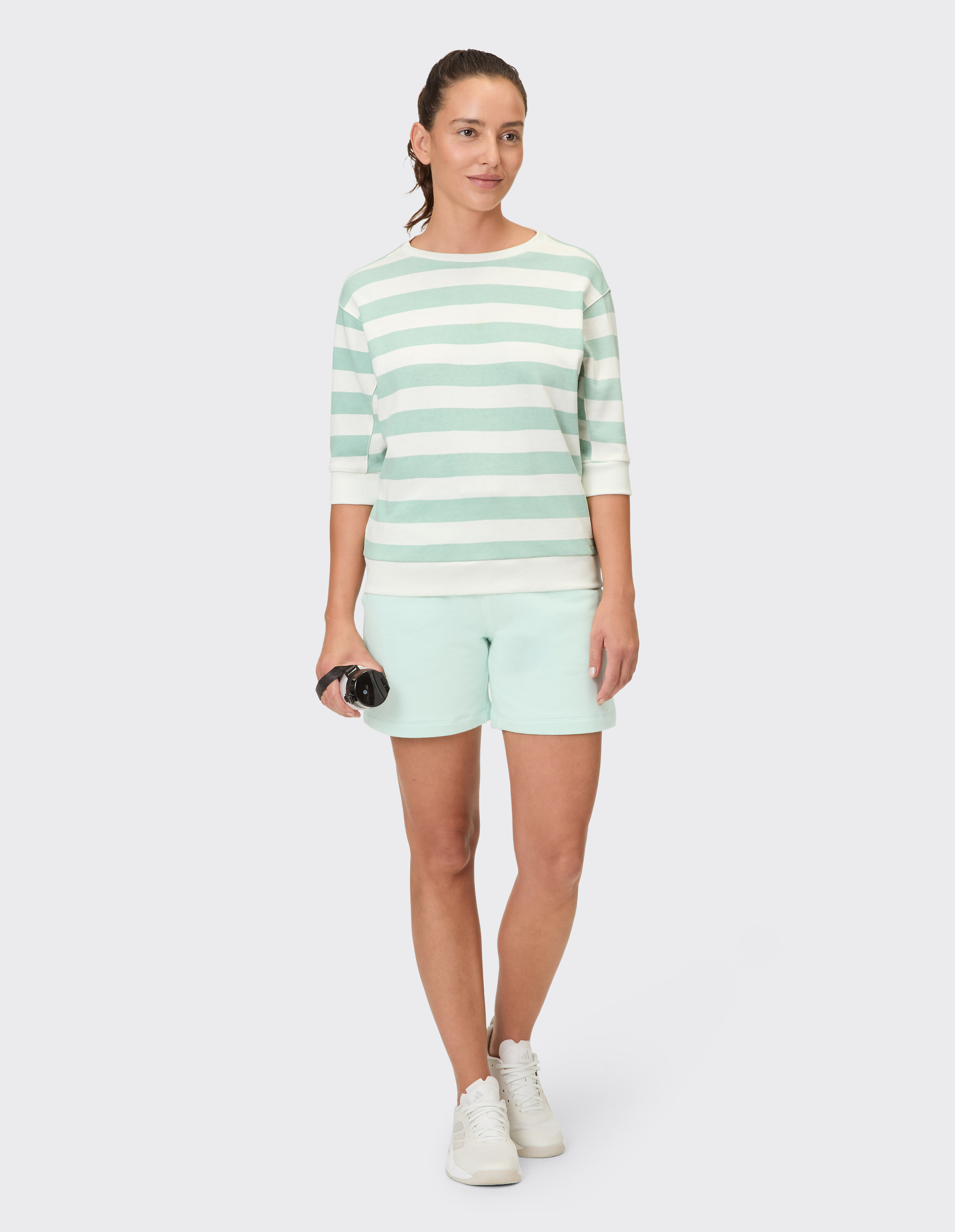 Frau in mintfarbenem, gestreiftem Pullover und passenden Shorts, perfekt für Freizeitausflüge.
