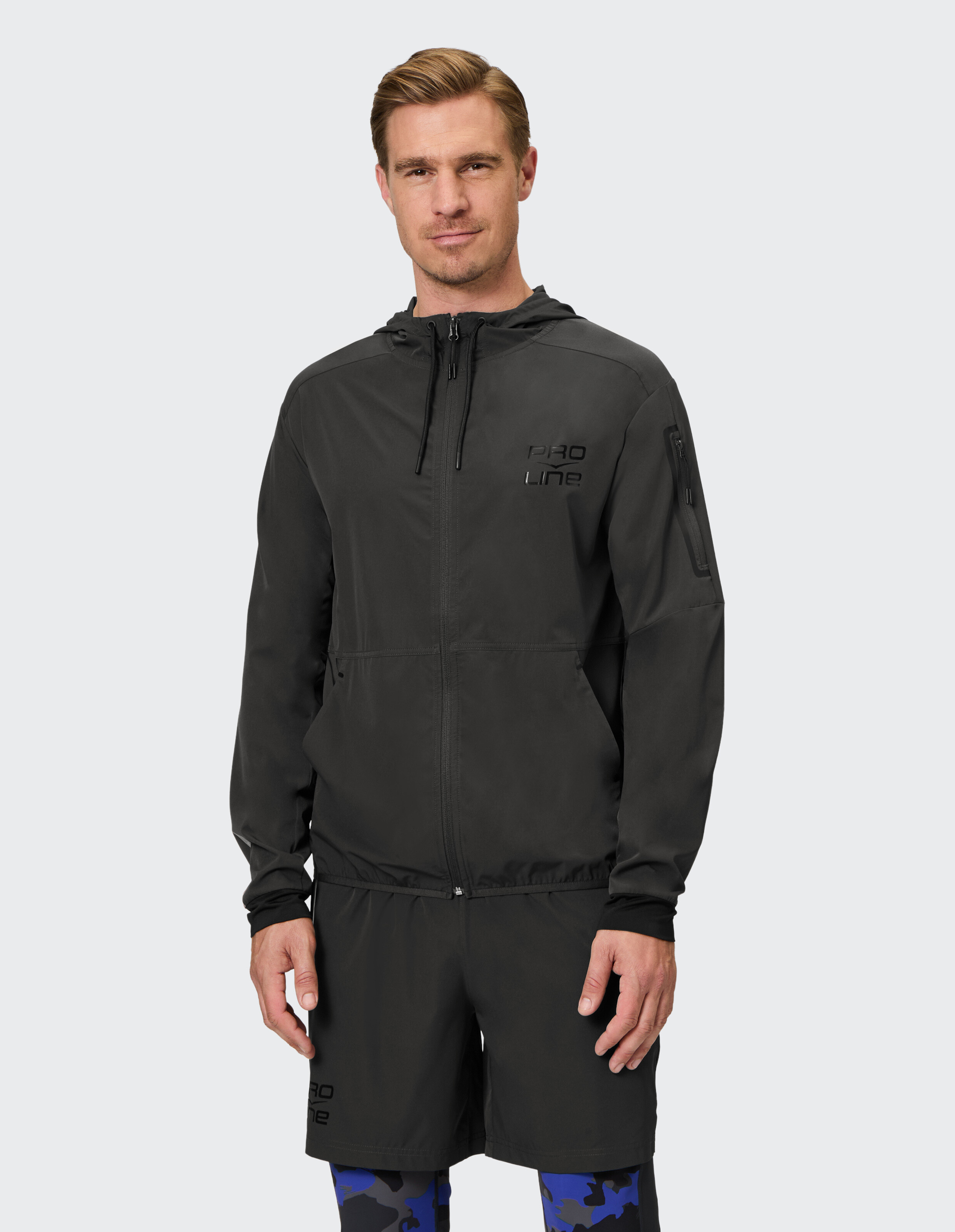 Mann in schwarzer leichter Jacke und Shorts, ideal für lässige Outdoor-Kleidung.