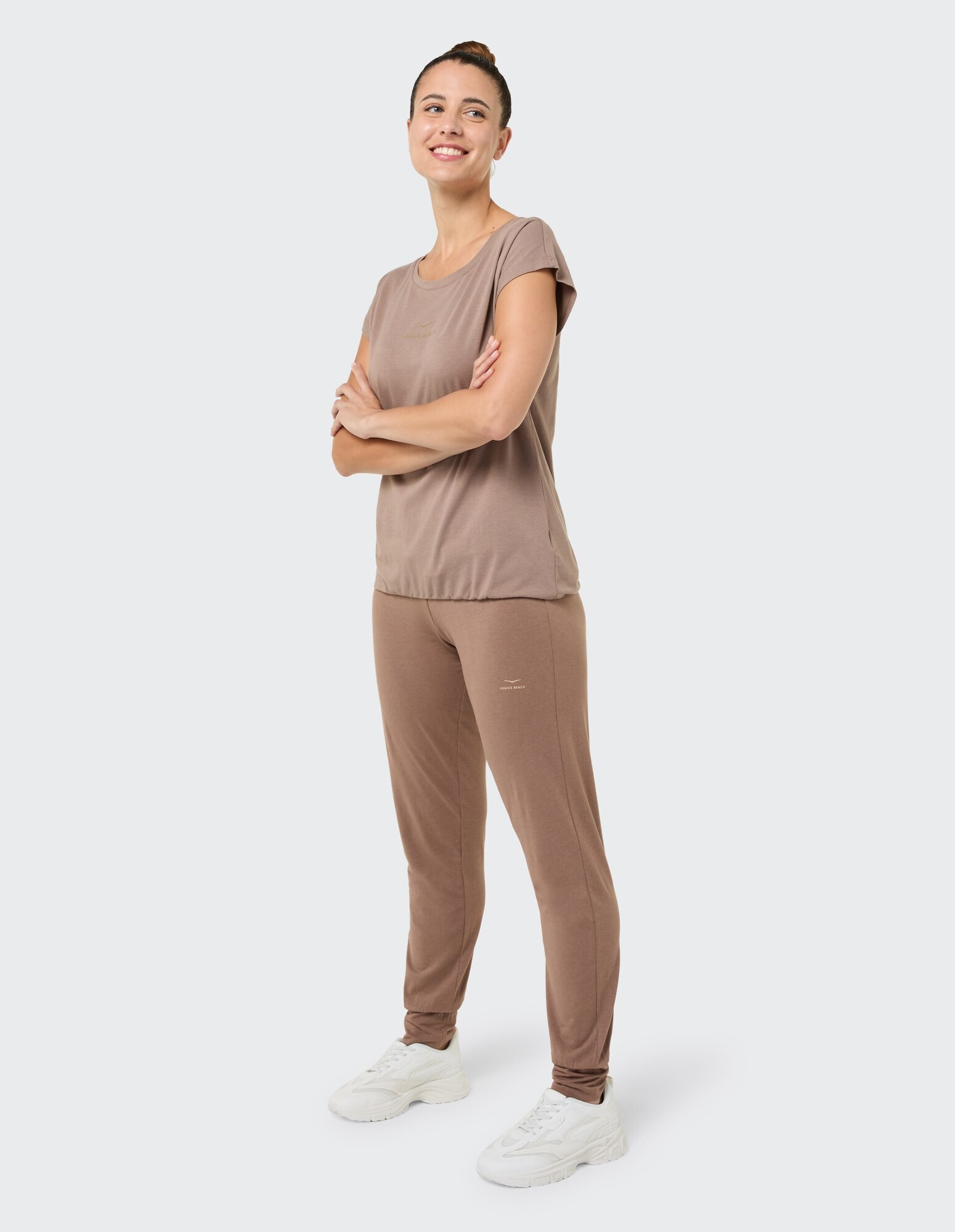 Lächelnde Frau in braunem Freizeitoberteil und passender Jogginghose, perfekt zum Entspannen.
