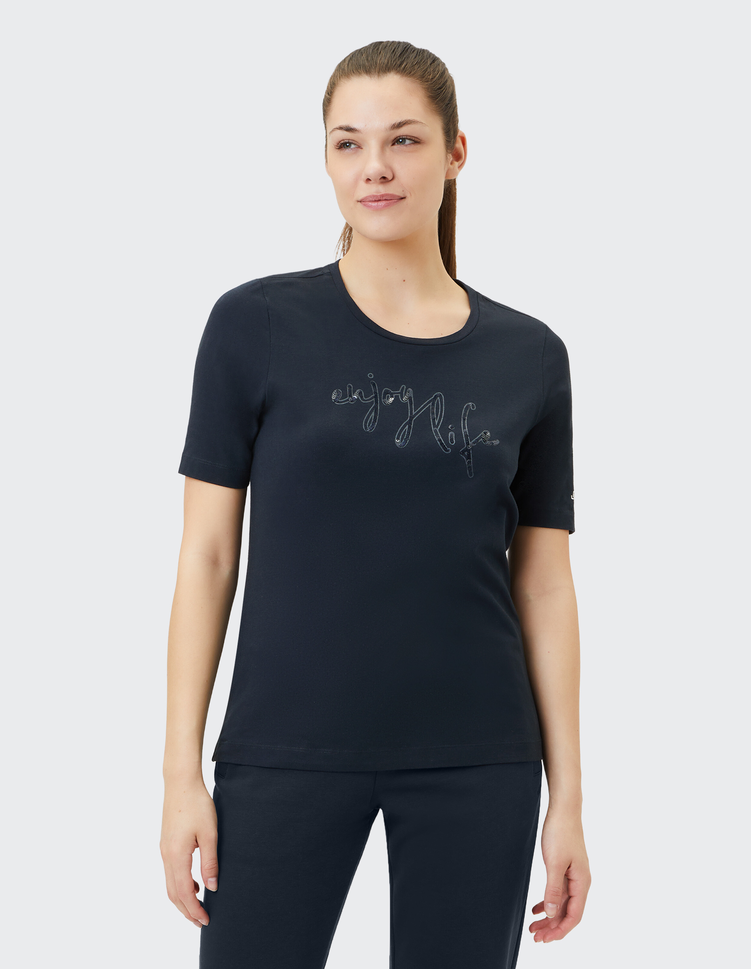 Frau trägt ein marineblaues ELBSAND-T-Shirt mit „Enjoy Life“-Schriftzug für lässige Lounge-Kleidung.