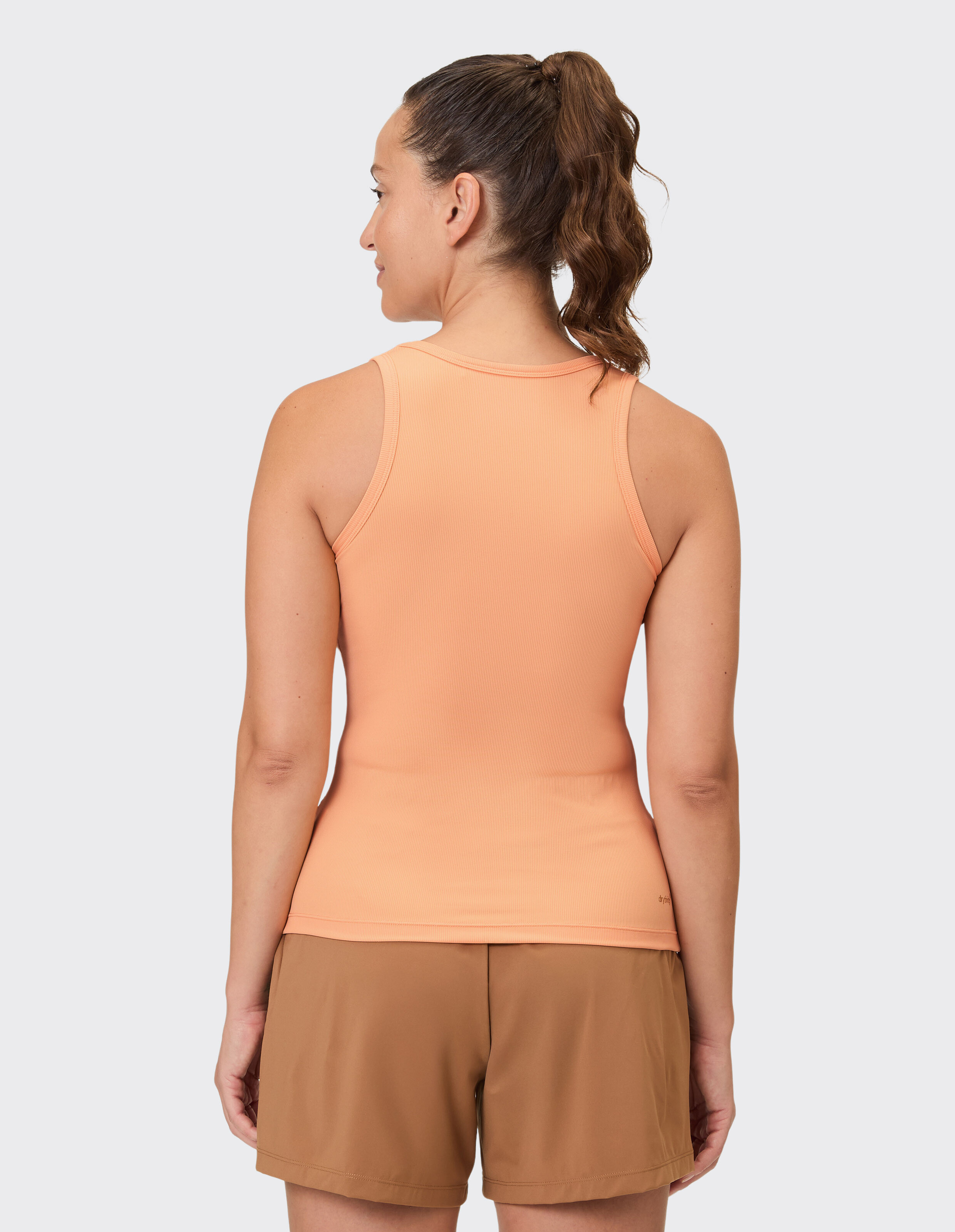 Frau trägt ein pfirsichfarbenes Venice Beach Brenda-Tanktop, Rückansicht, lässiger Stil.