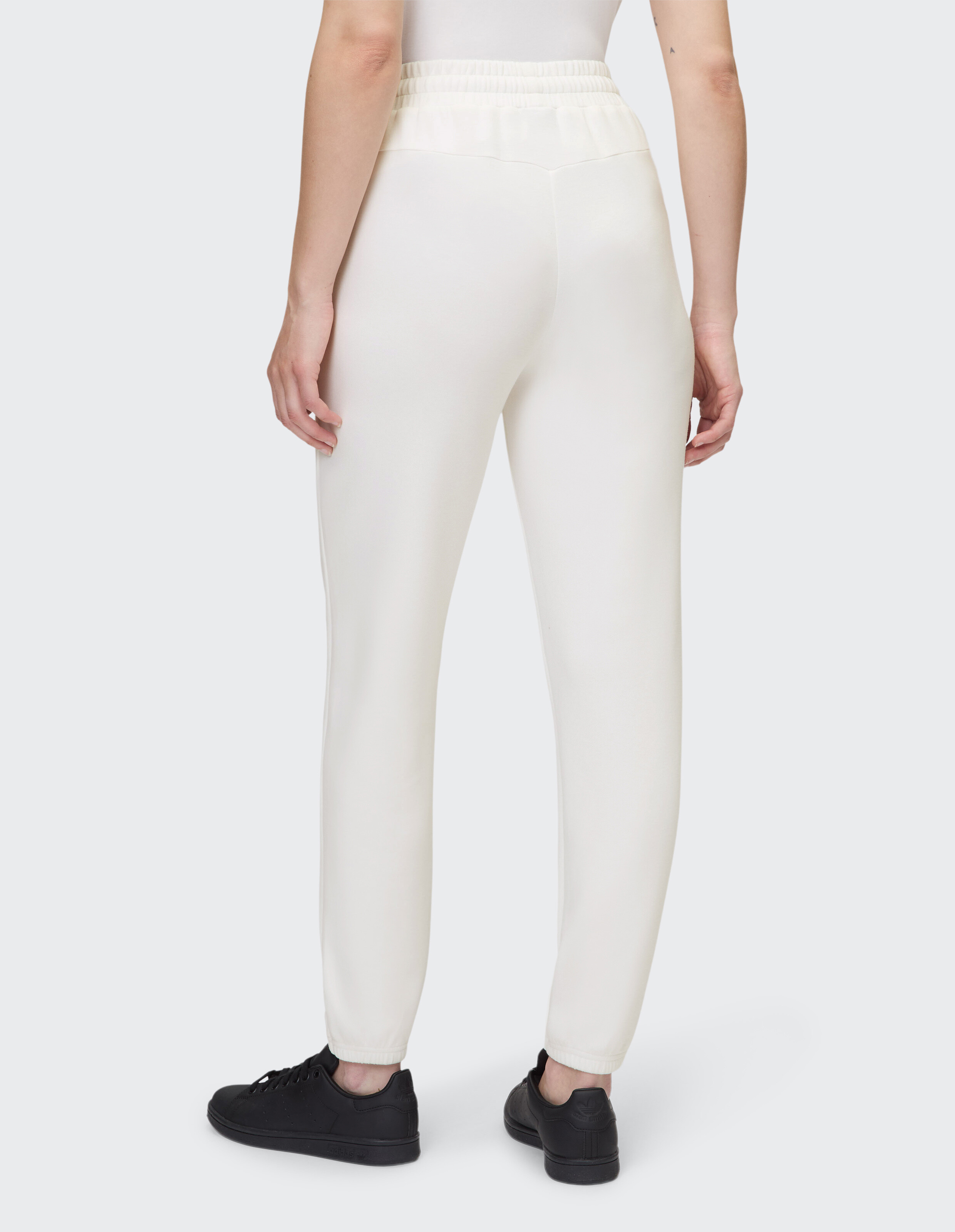 Rückansicht einer cremefarbenen Jogginghose mit elastischem Bund und Bündchen am Saum.