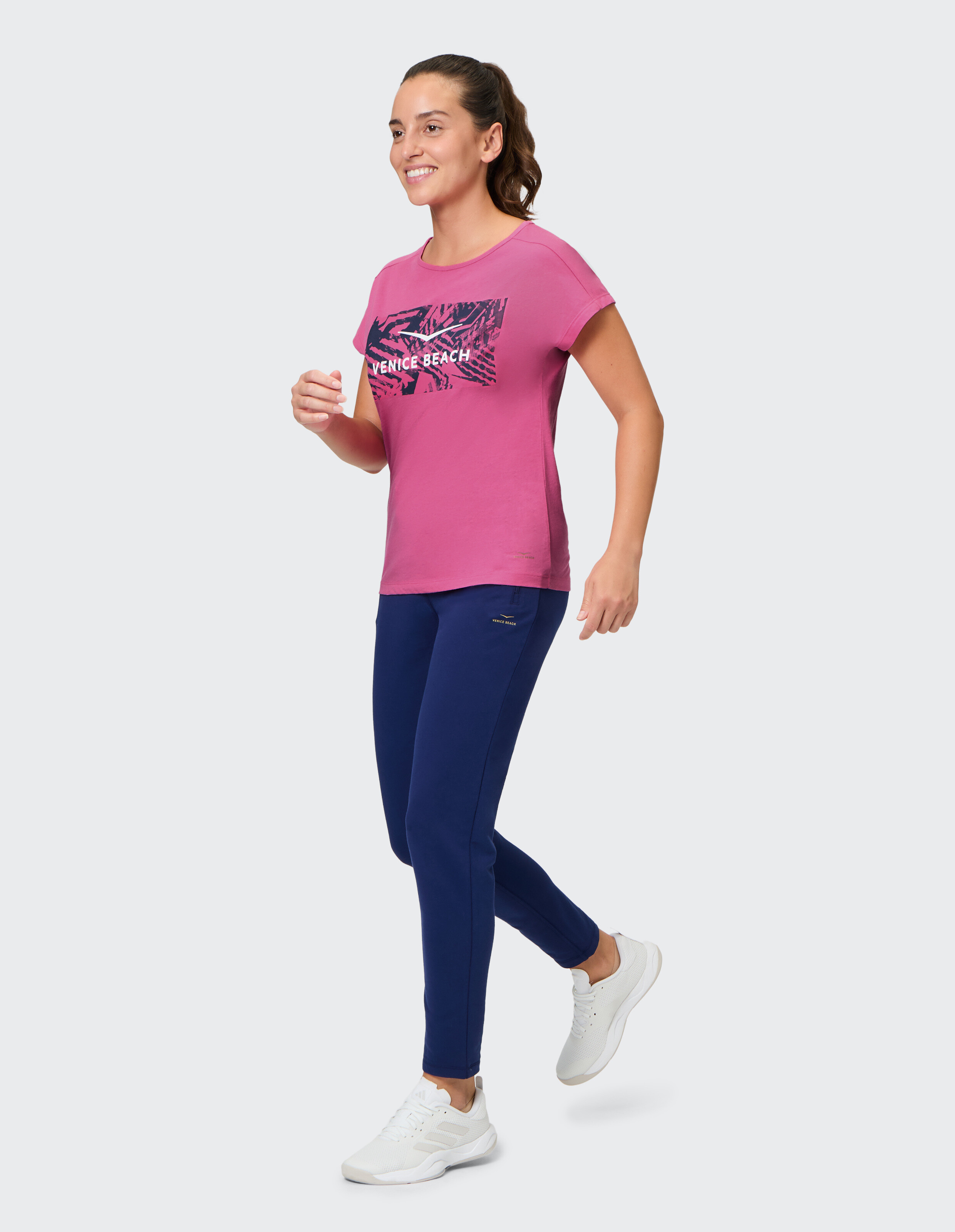 Frau trägt ein rosafarbenes Venice Beach Kurzarmshirt Tia mit einer lässigen blauen Hose.