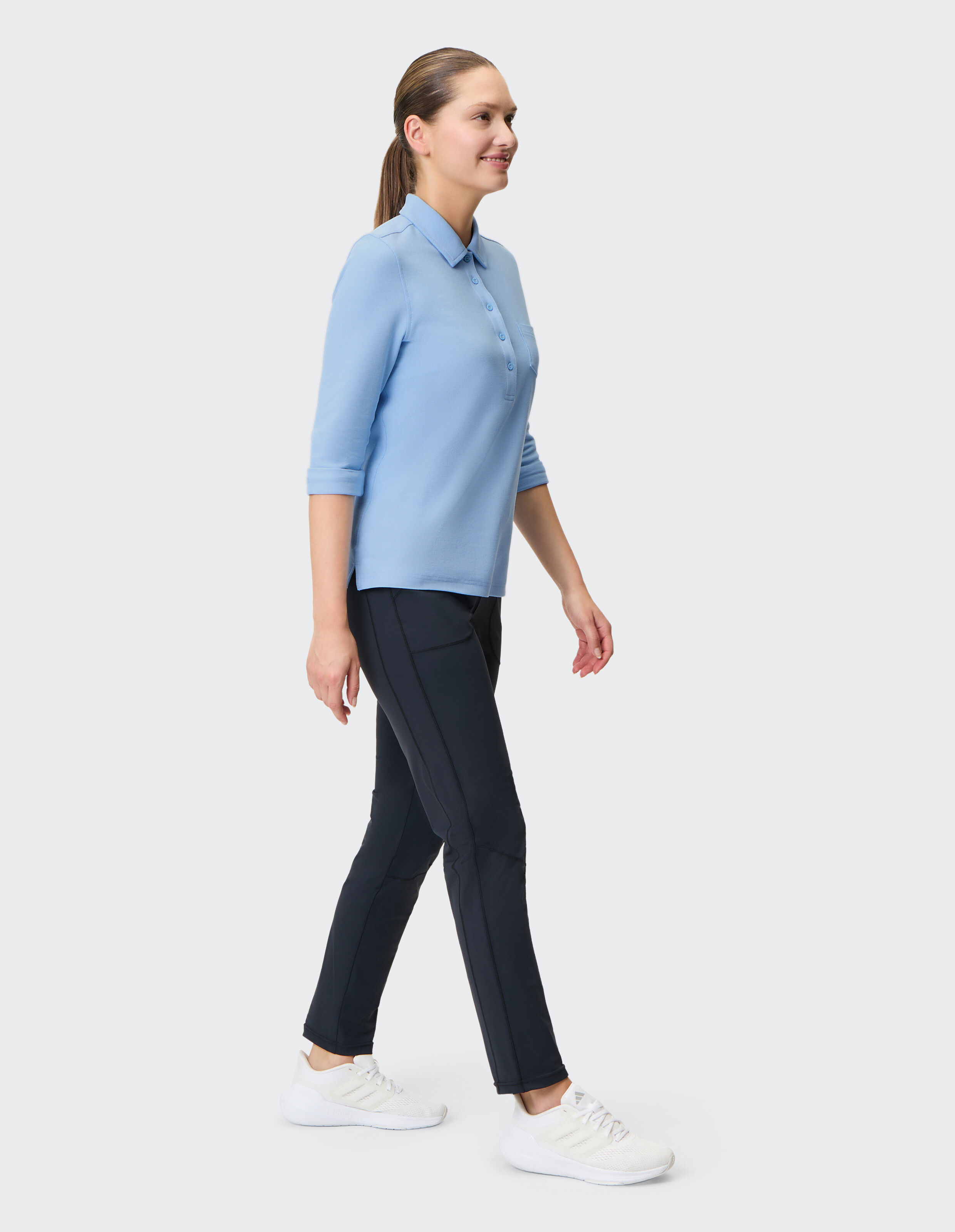 Frau in hellblauem Polo und dunkelblauer Hose, die lässigen Komfort und Stil präsentiert.