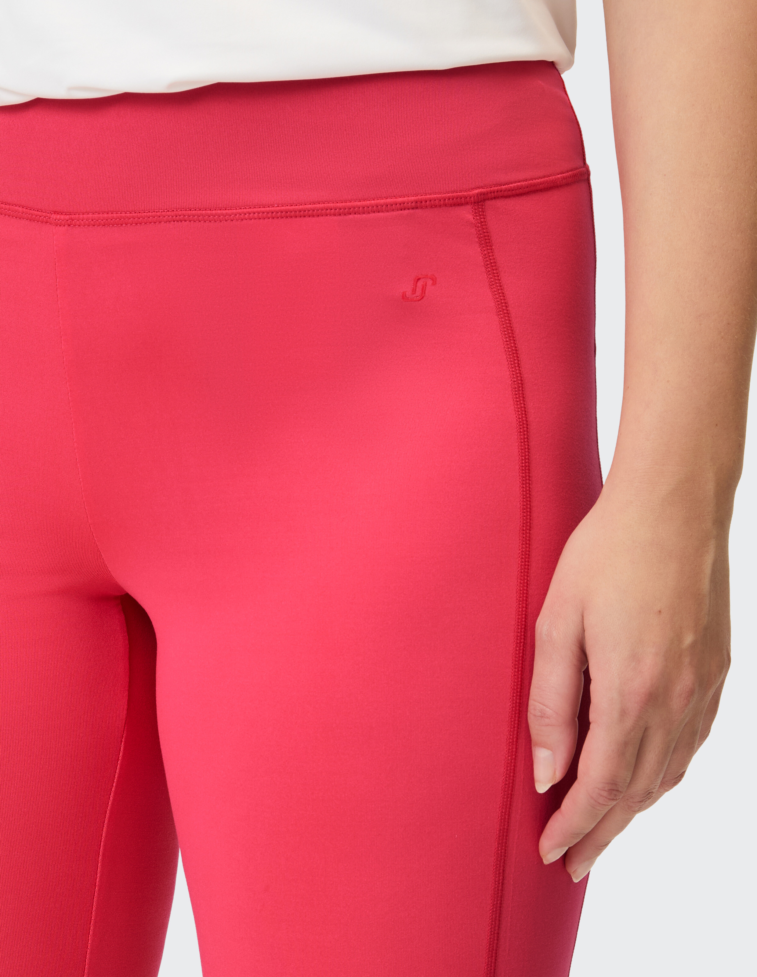 Ein rotes Damen-Sportoberteil mit einer dezenten Logo-Stickerei.